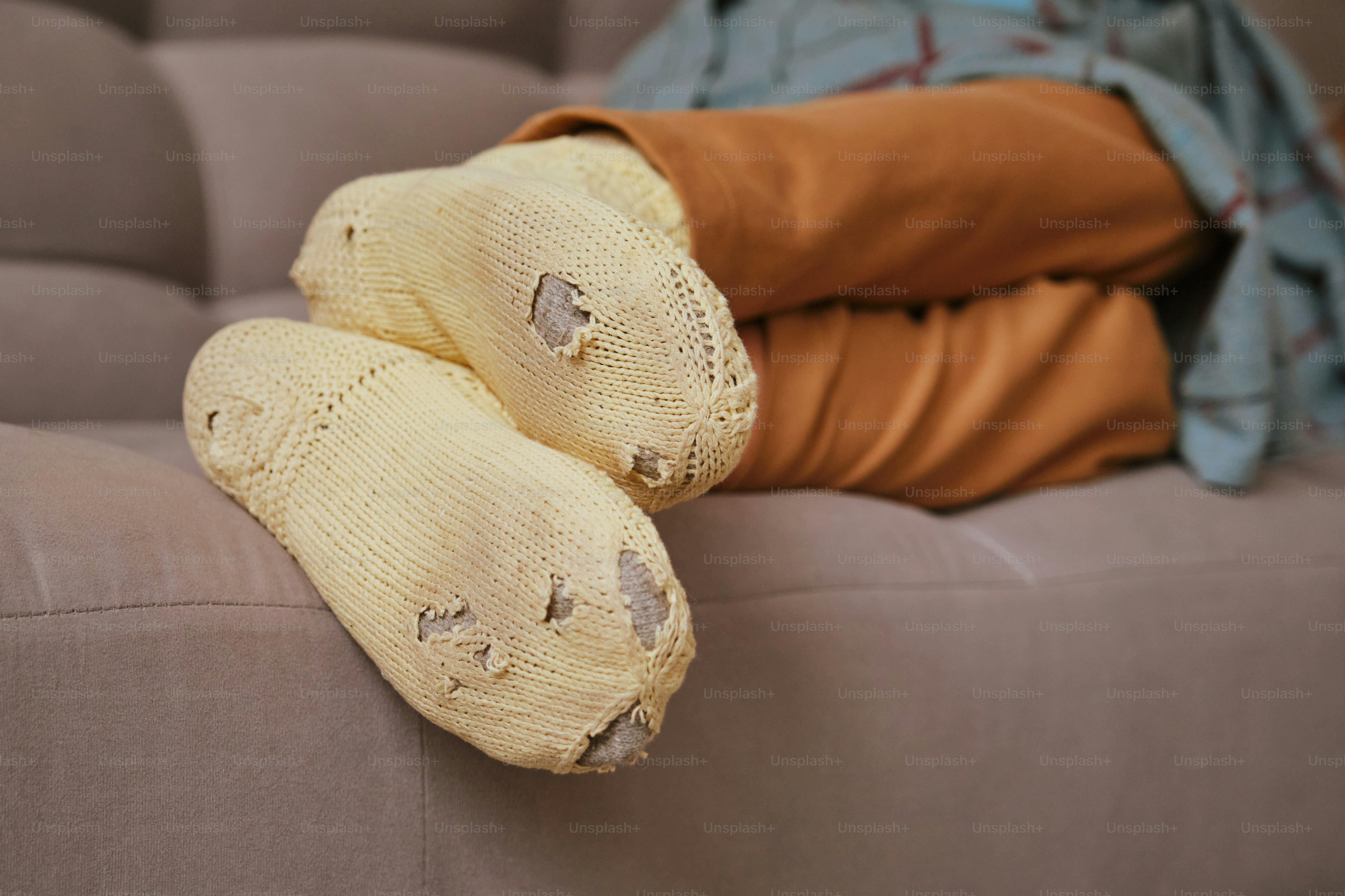 Getragene Socken an einer Person, die sich auf einer Couch ausruht