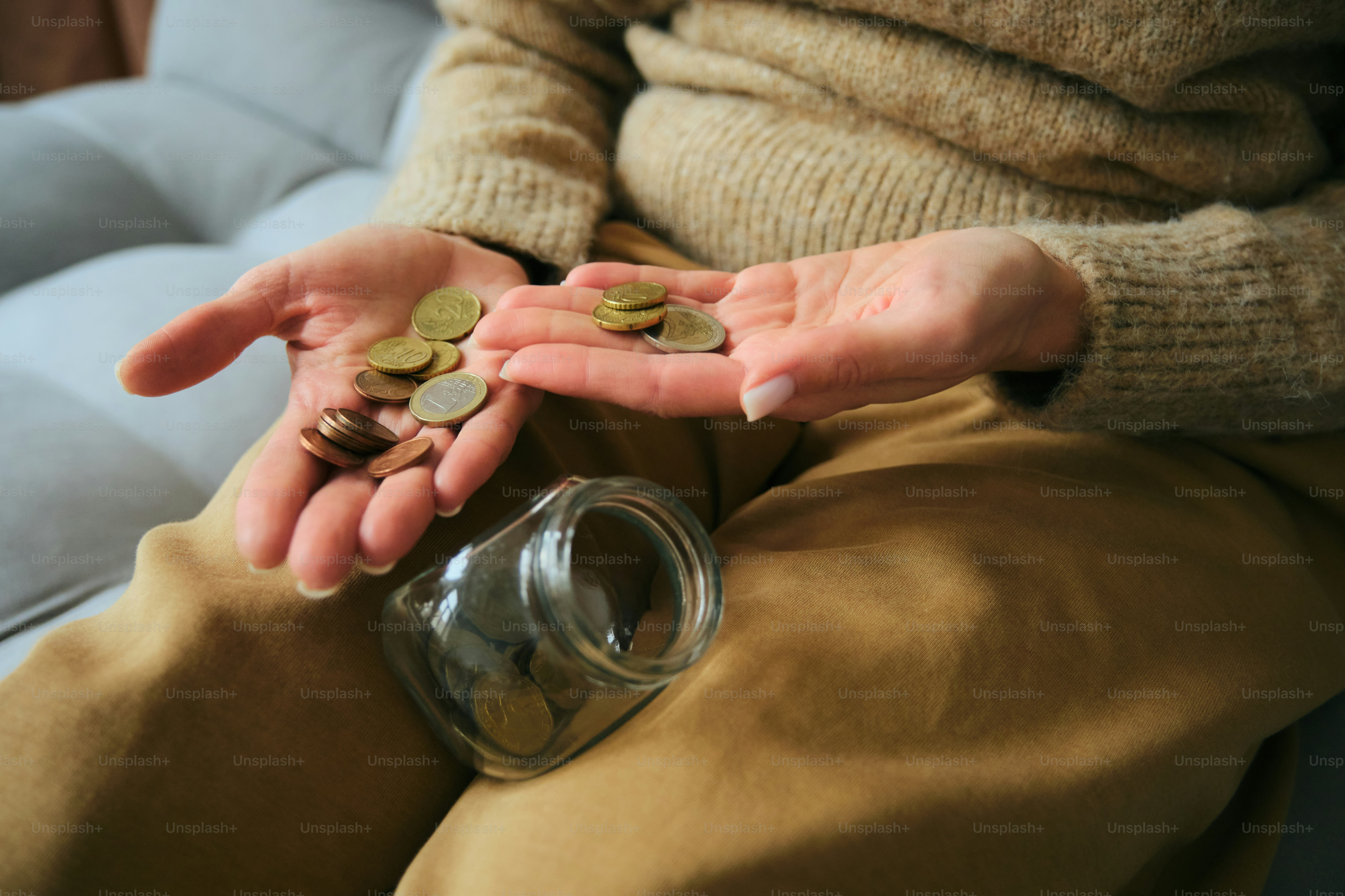 Hände halten Münzen in der Nähe eines Glases