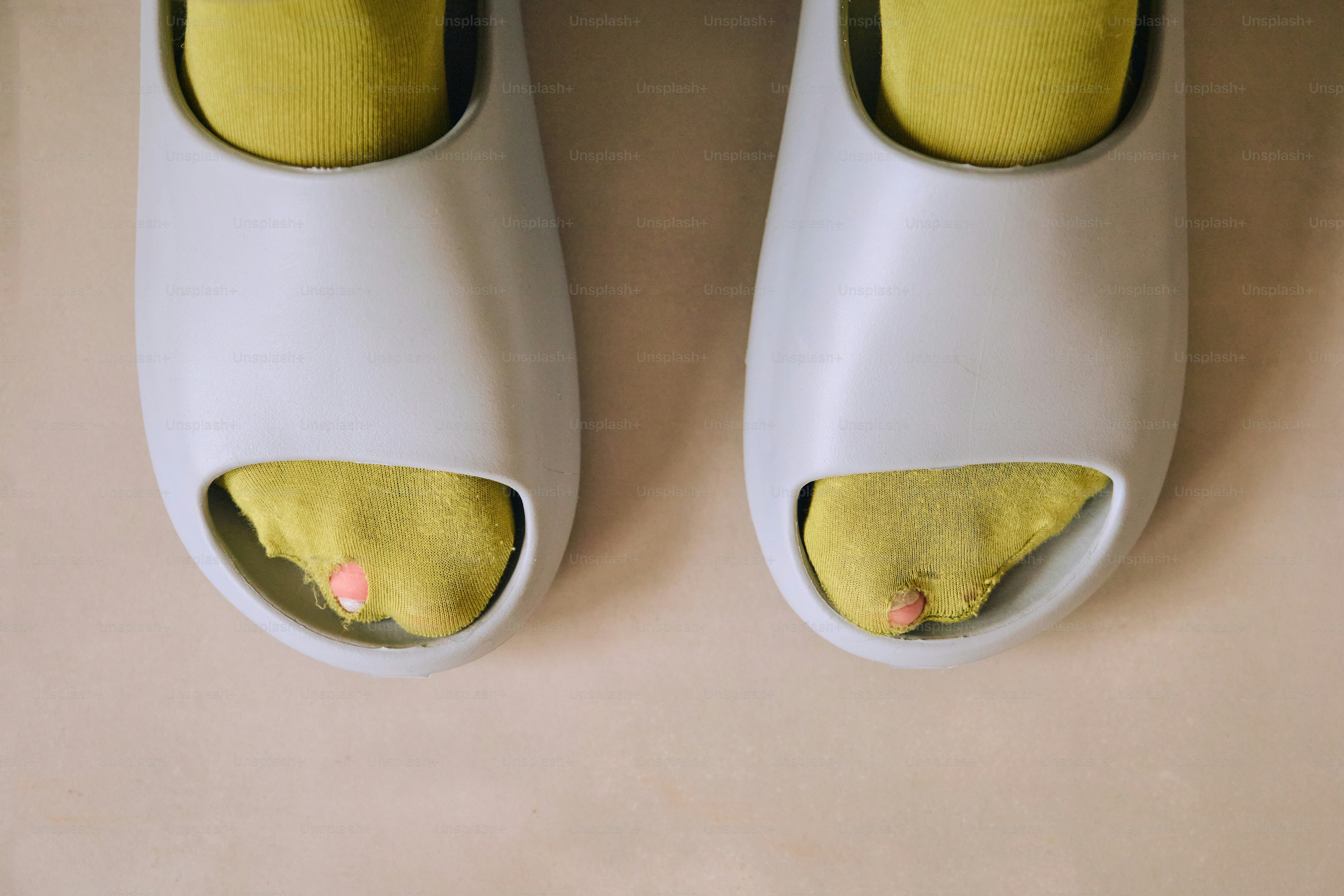 Füße in gelben Socken und weißen Pantoletten