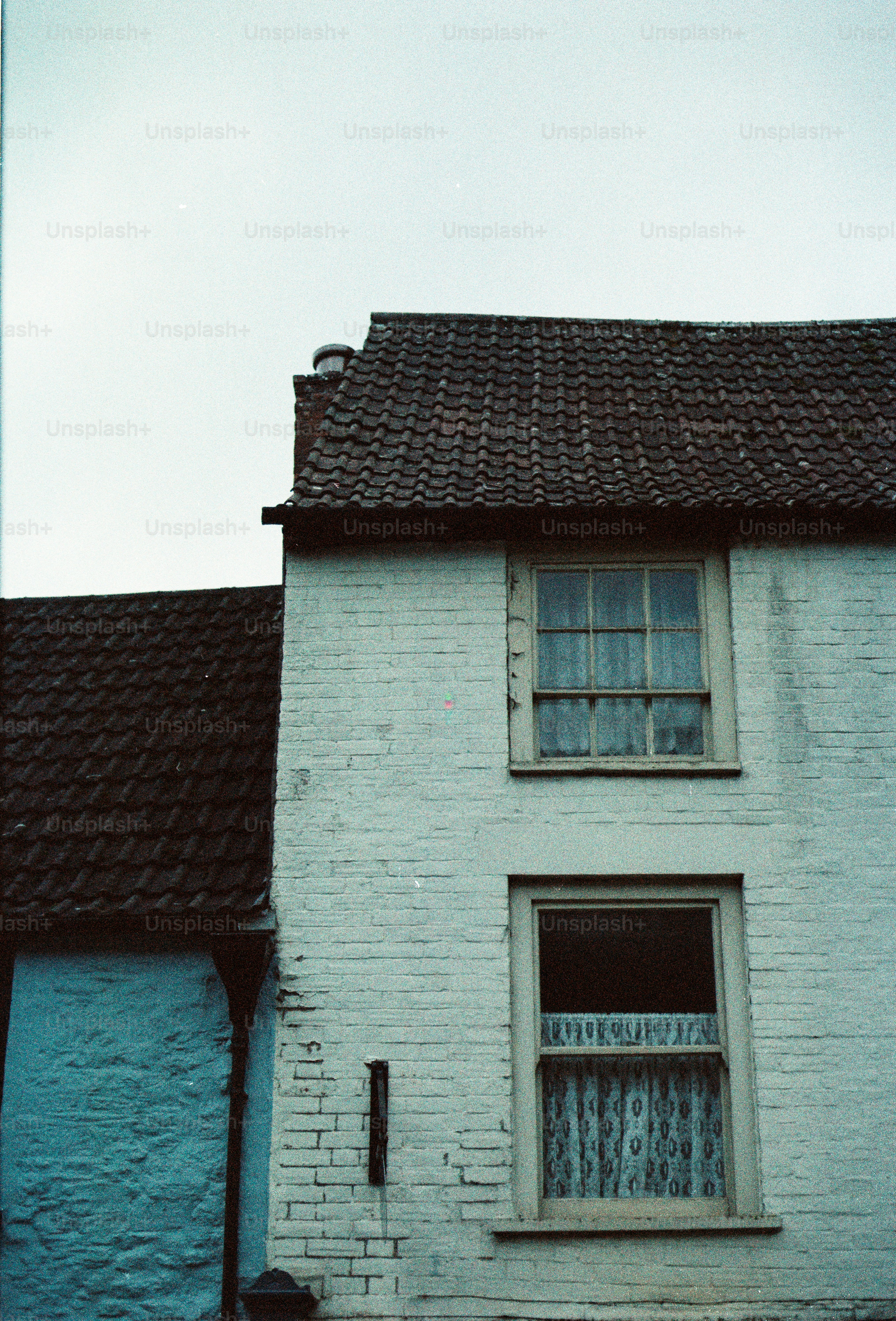 White brick house with tiled roof and windows.