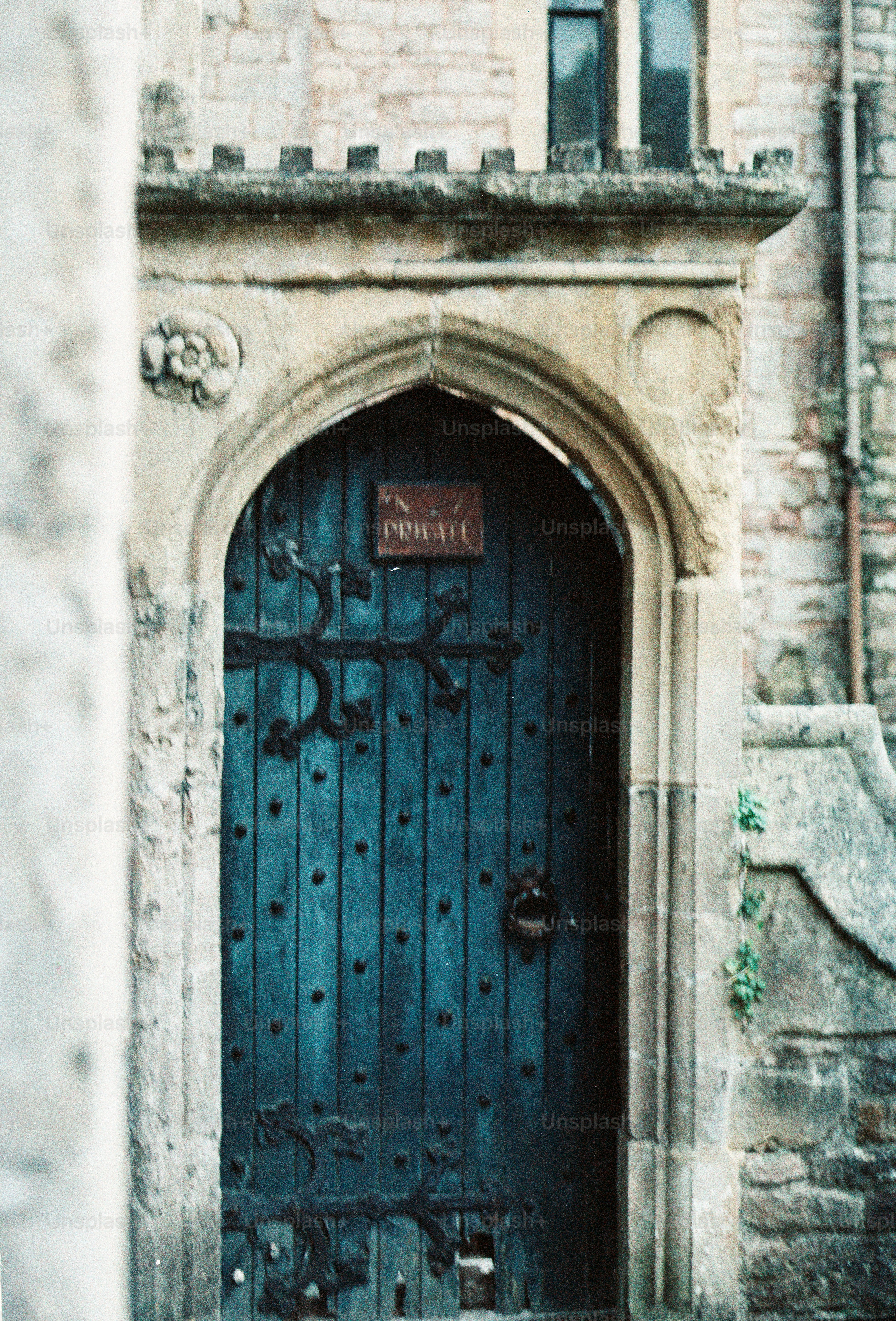 Old wooden door with ornate metalwork and stone archway.