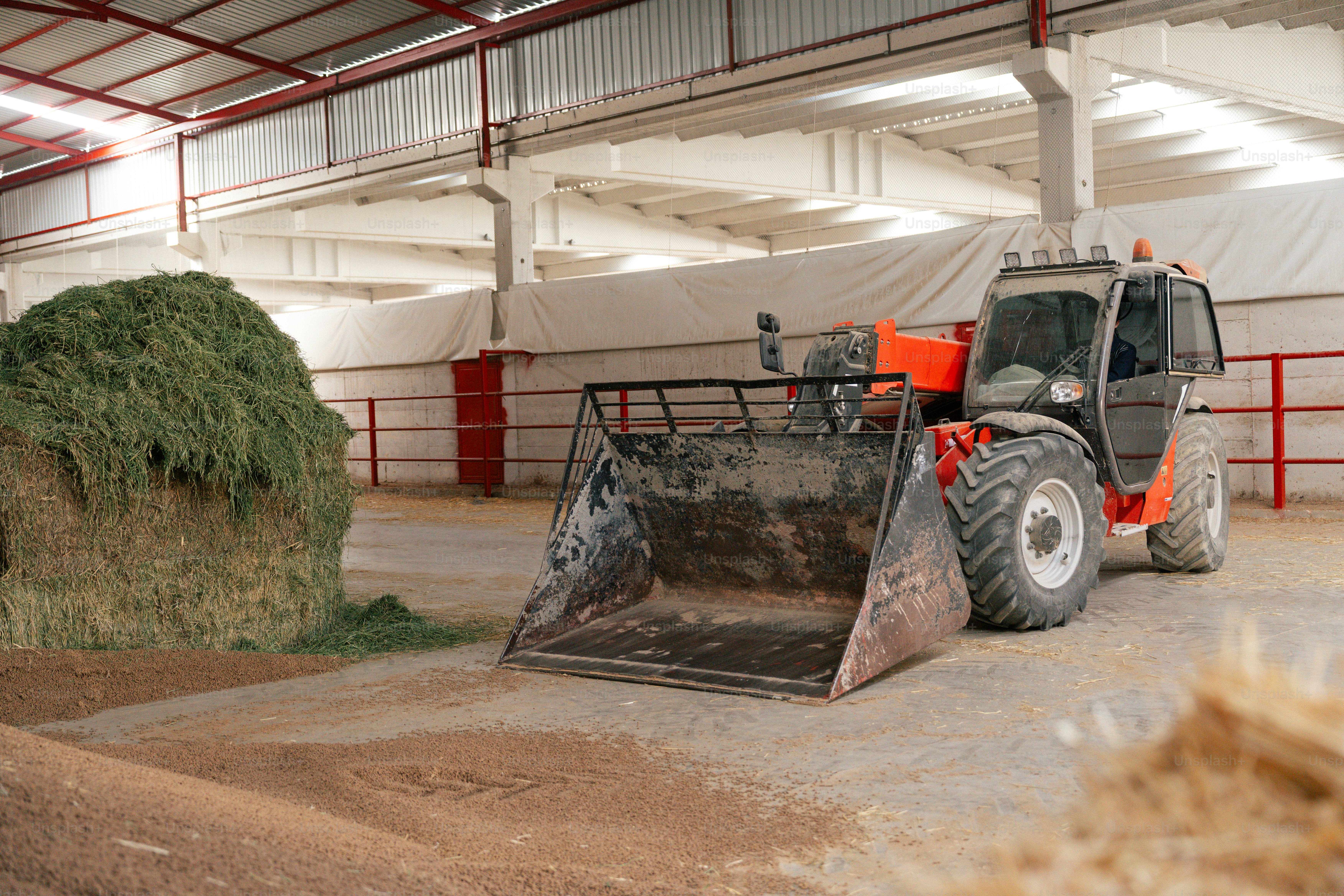 Telescopic loader next to a large hay bale.