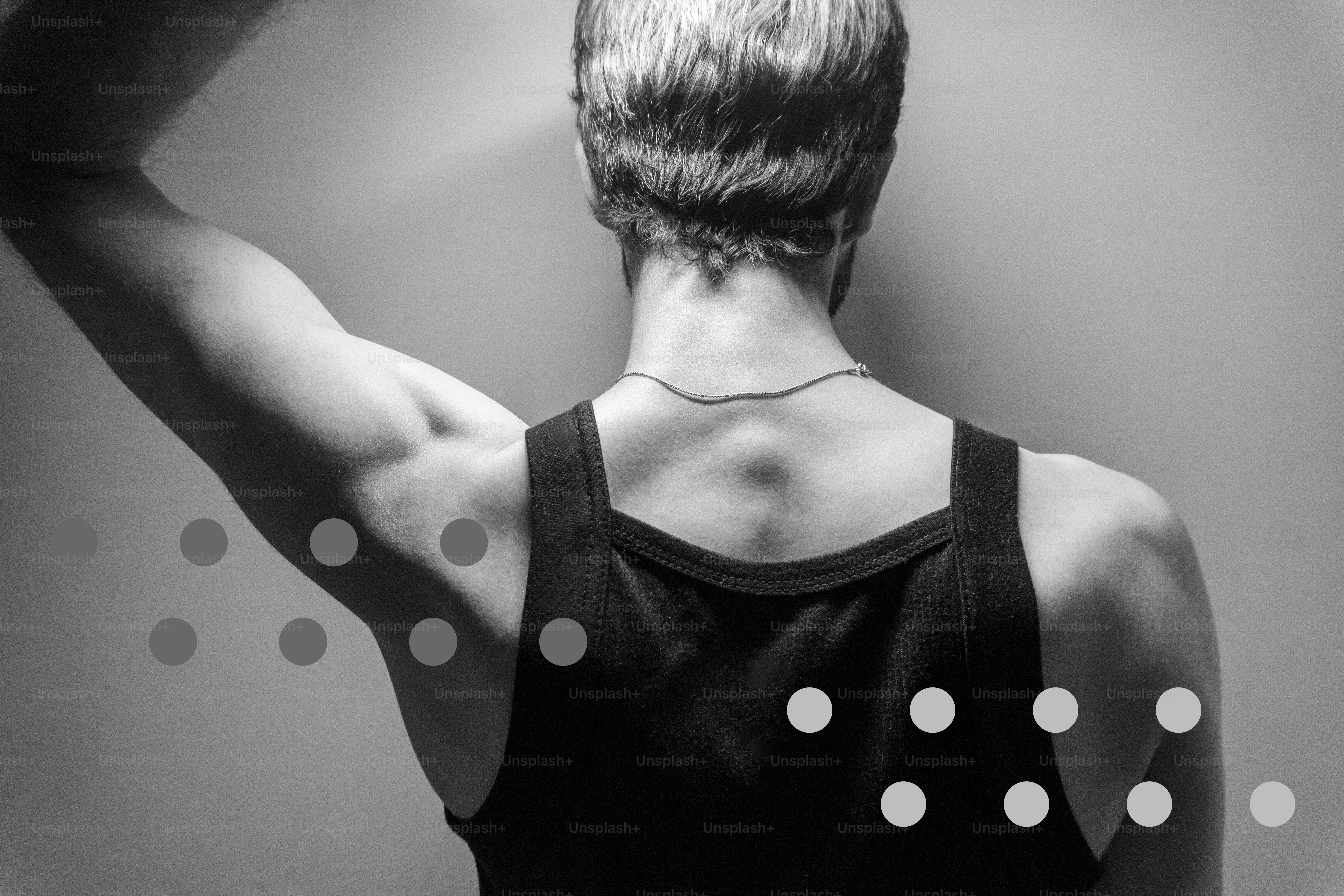Man's back with muscular arm and tank top.