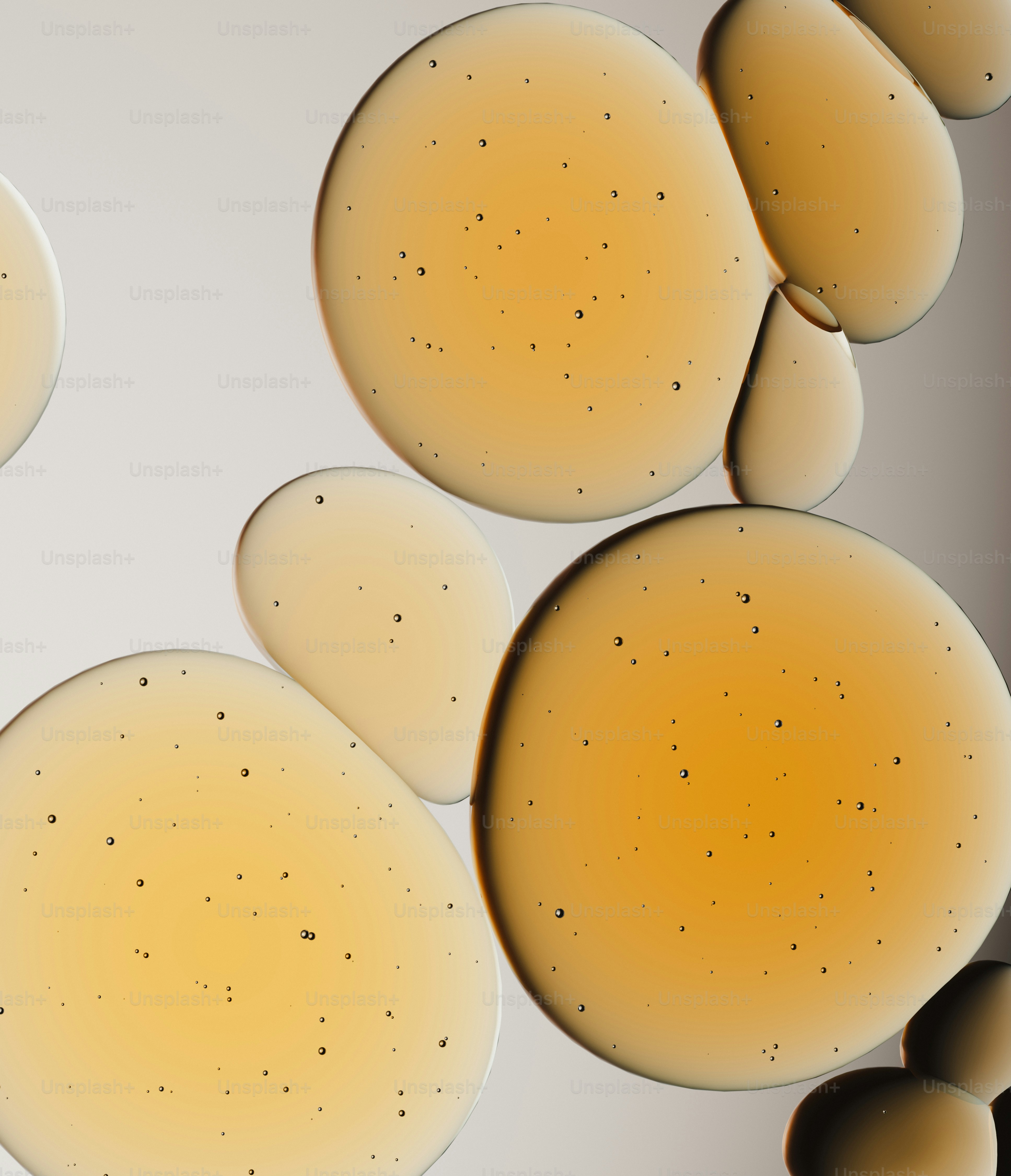 Close-up tetesan minyak emas dengan latar belakang netral.