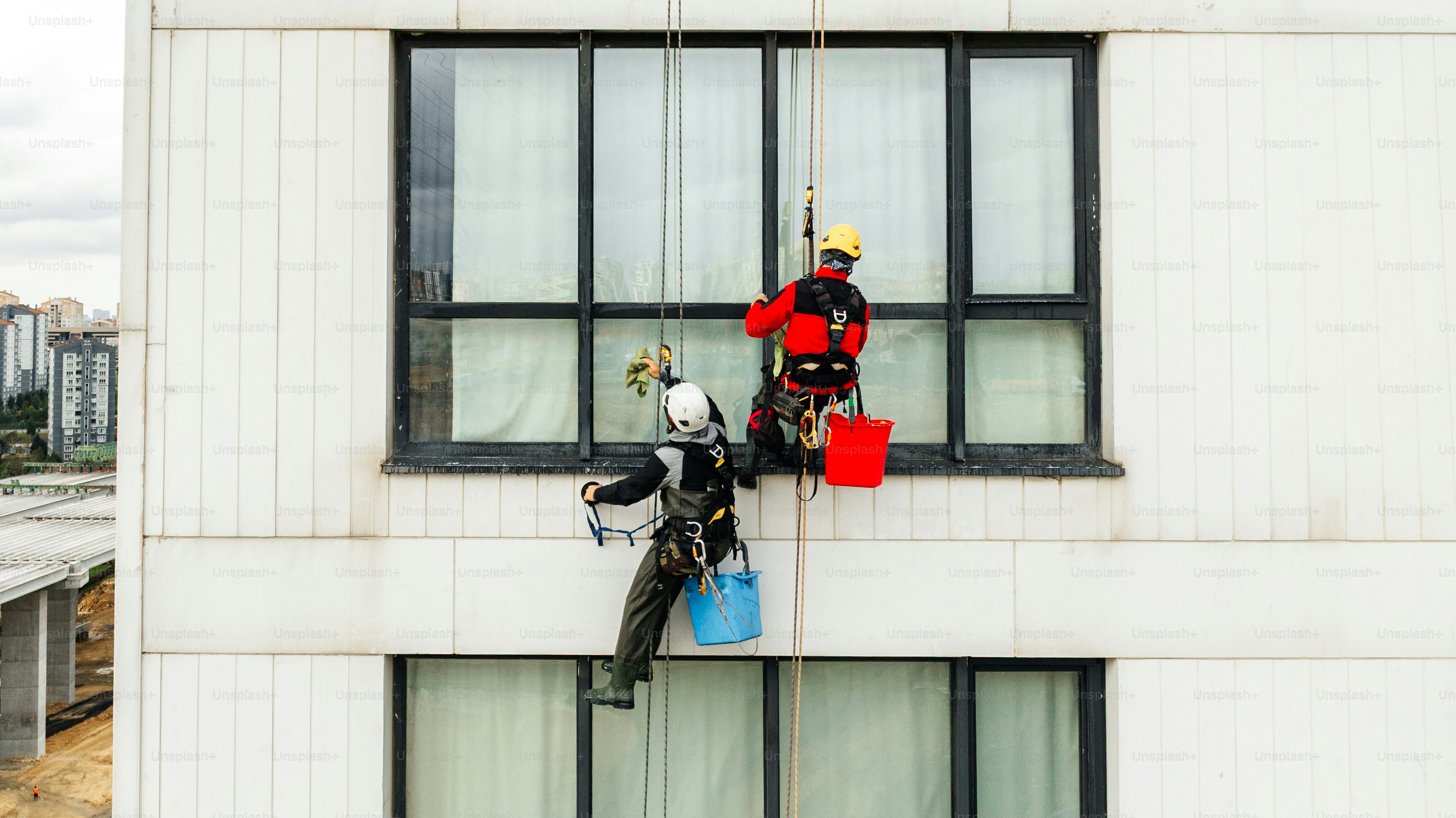 Workers clean windows on a modern building exterior. photo – Risk ...