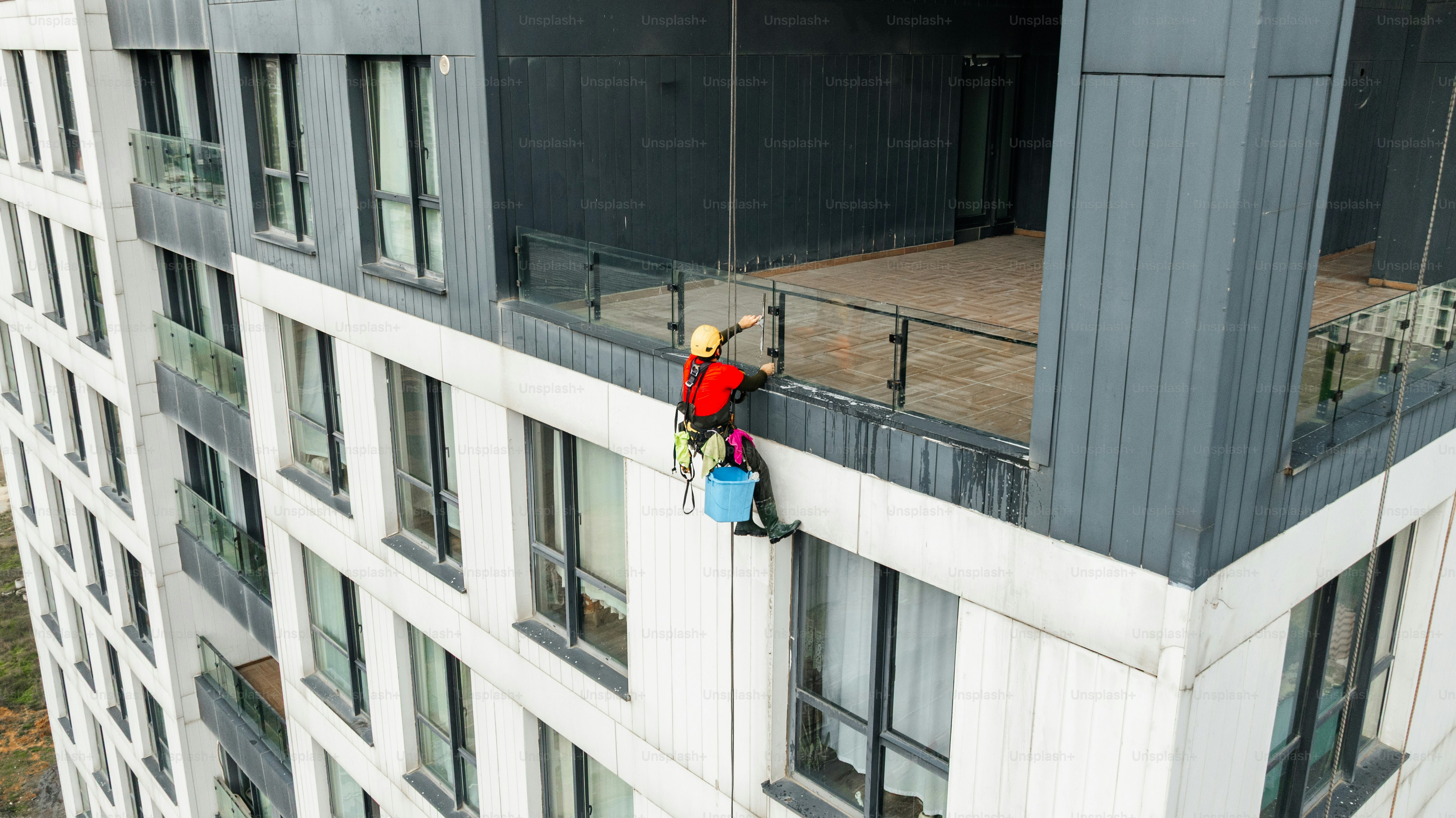 Window cleaner working on high-rise building exterior photo – Rope ... - High Rise Building Exterior Maintenance Strategy