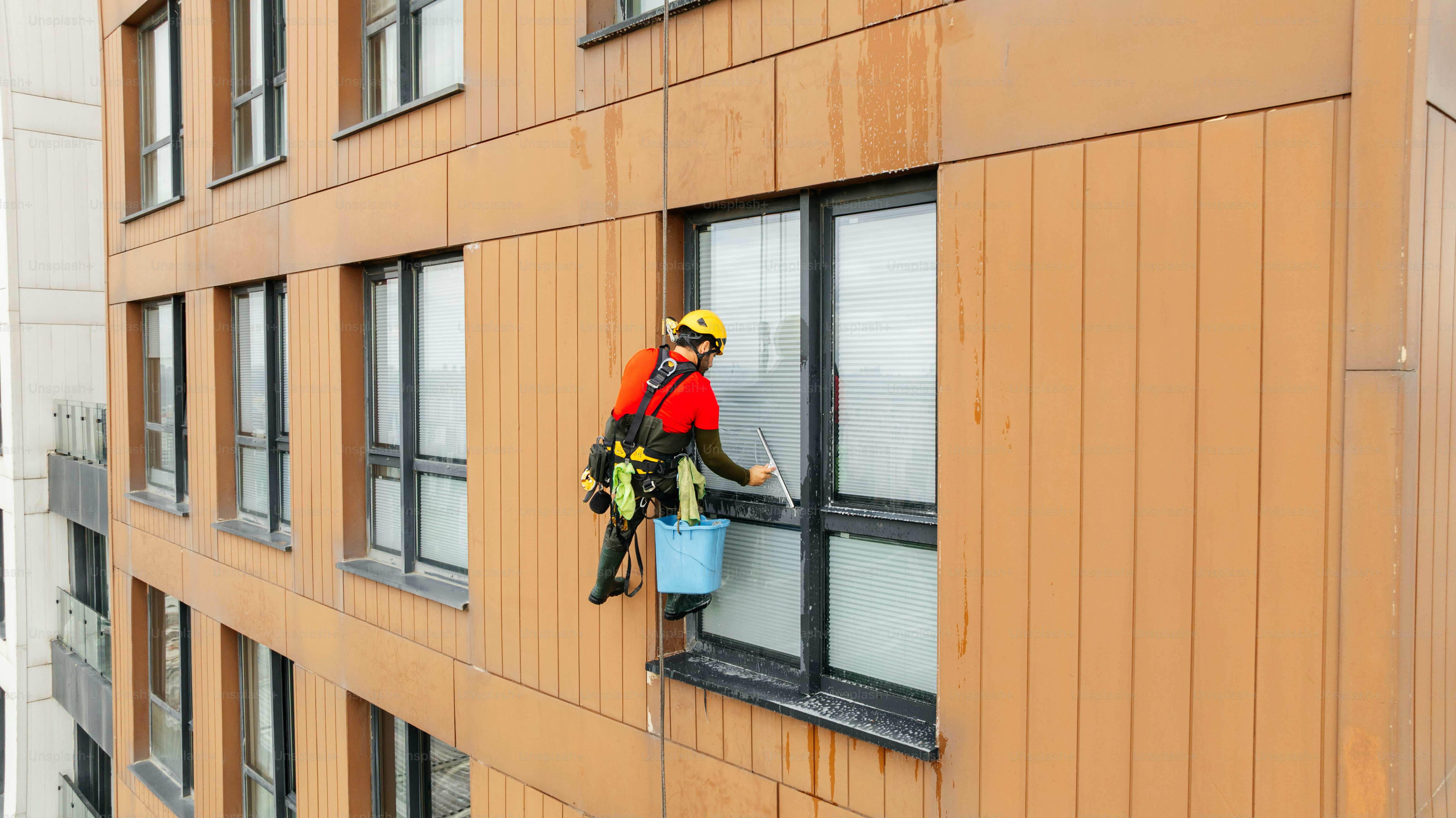 Worker cleaning windows on modern building exterior photo – Cleaner ...