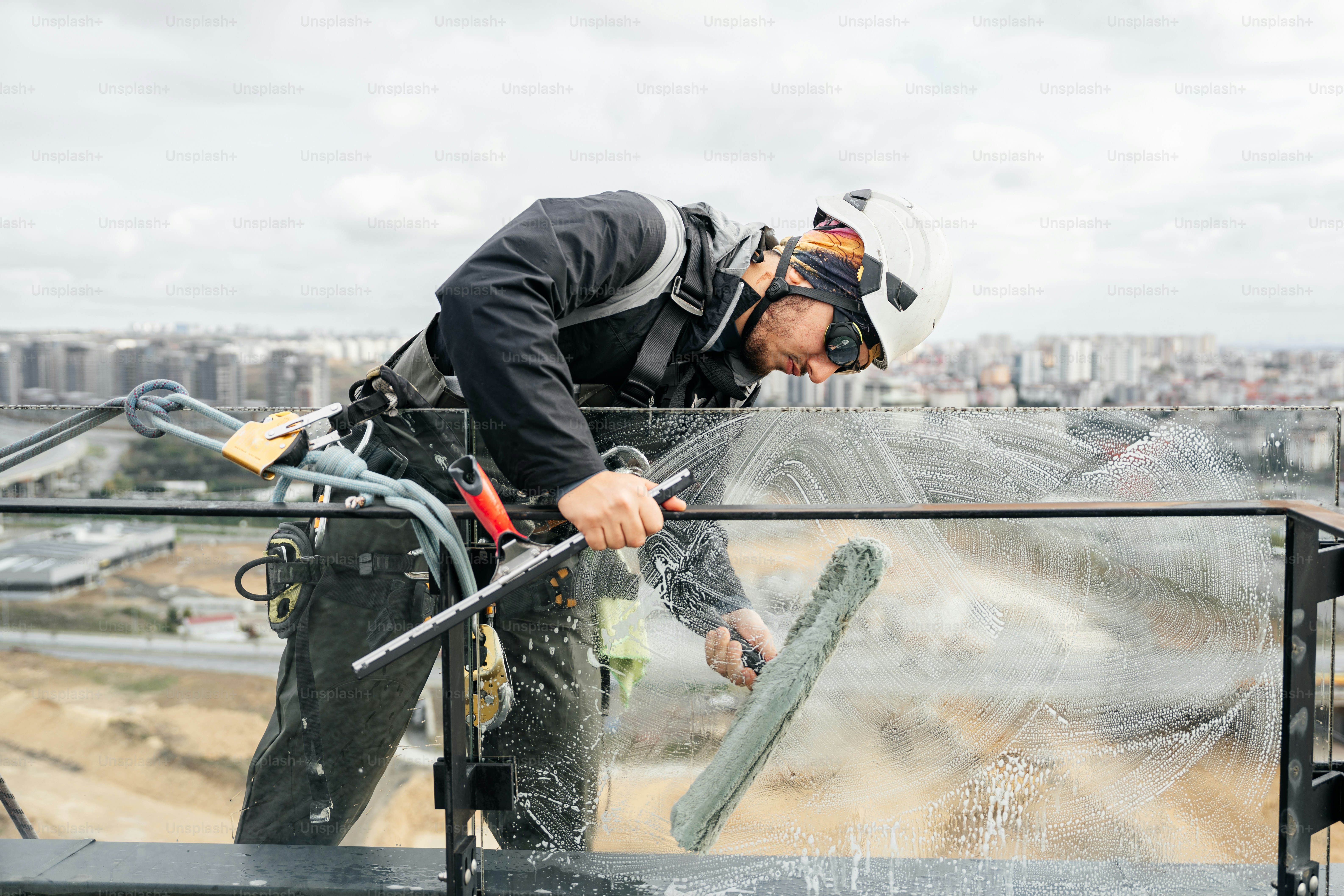 Window cleaner working high above city buildings