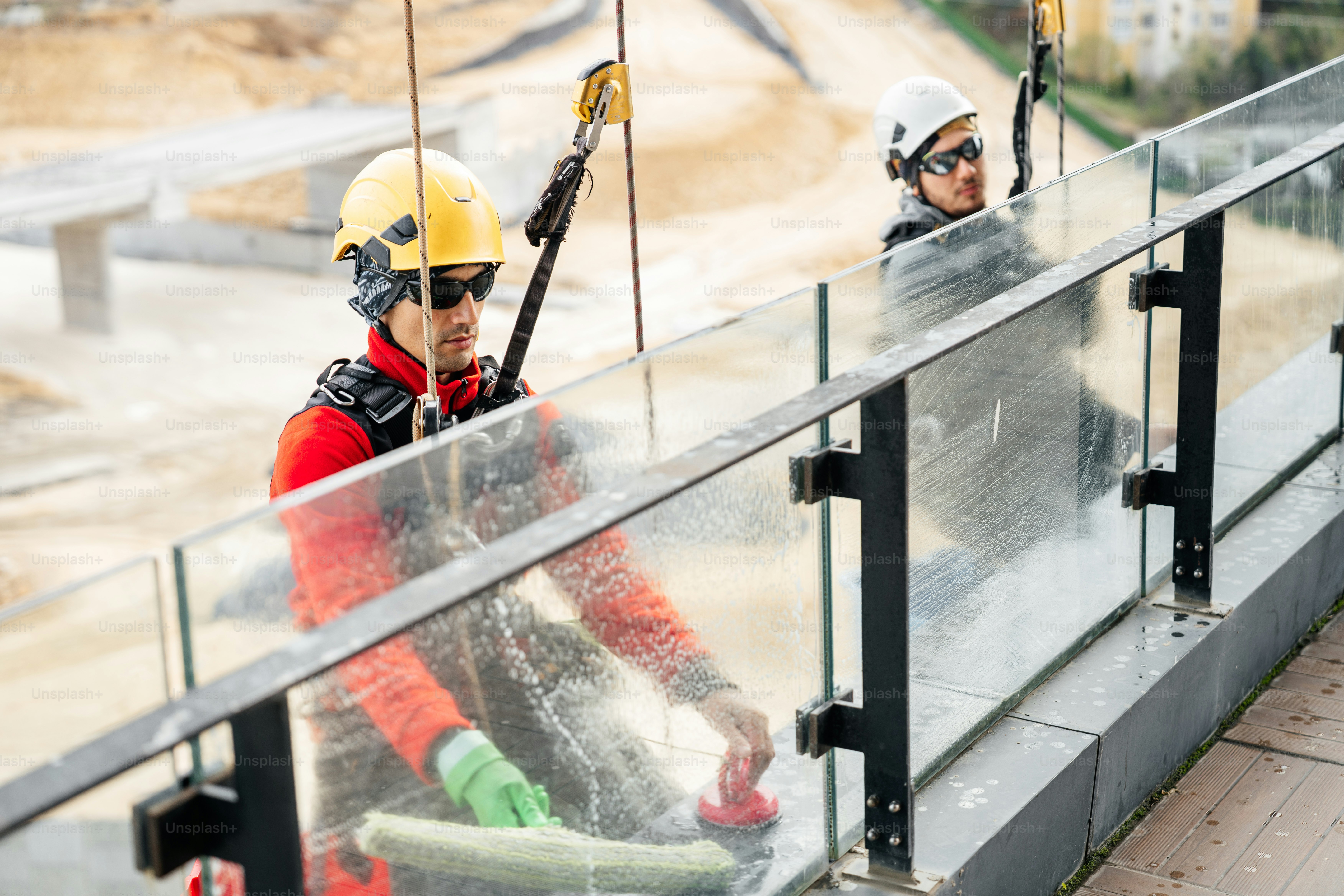 Workers cleaning glass railing on a high-rise building. photo ...