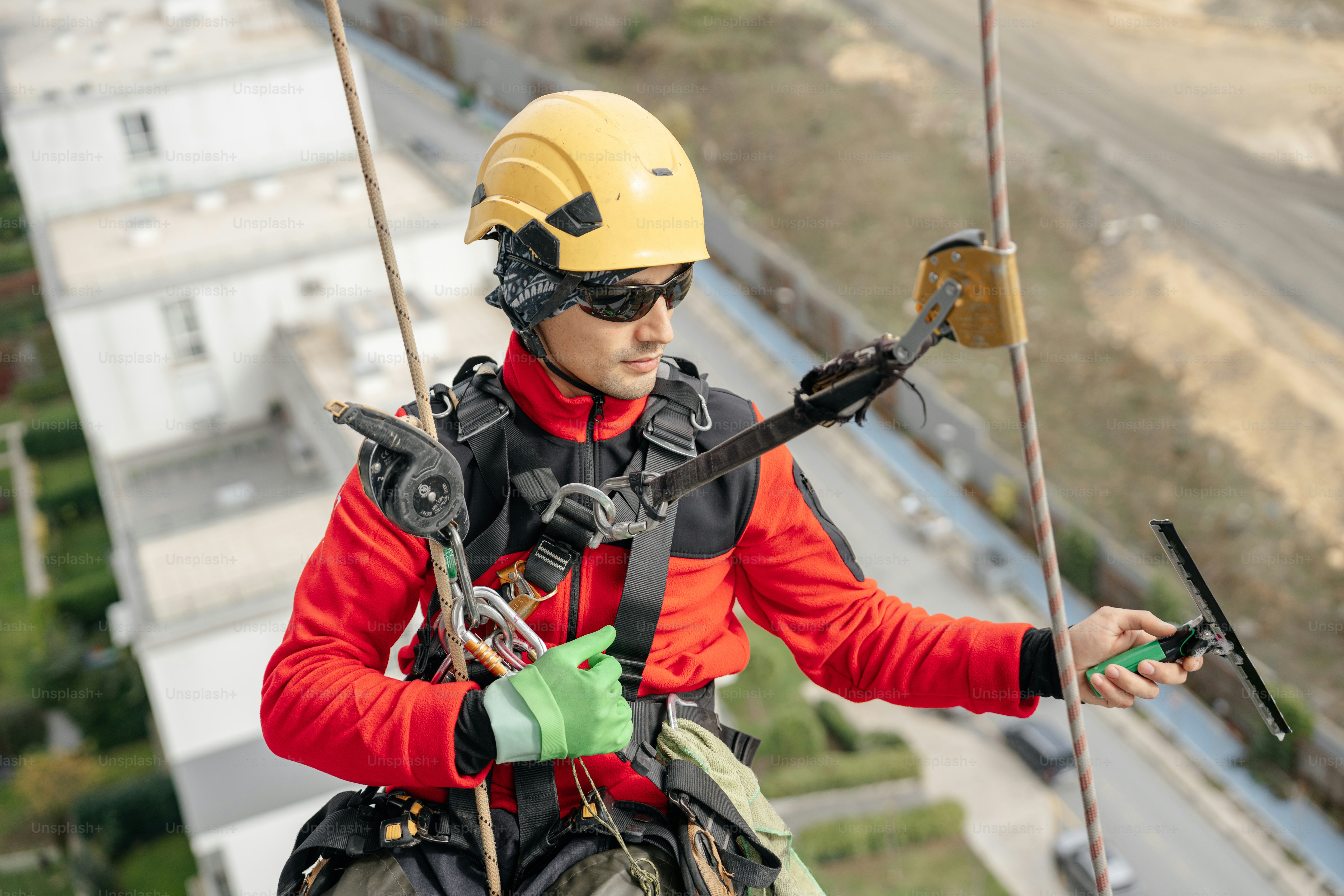 Rope access technician cleaning high rise building windows.