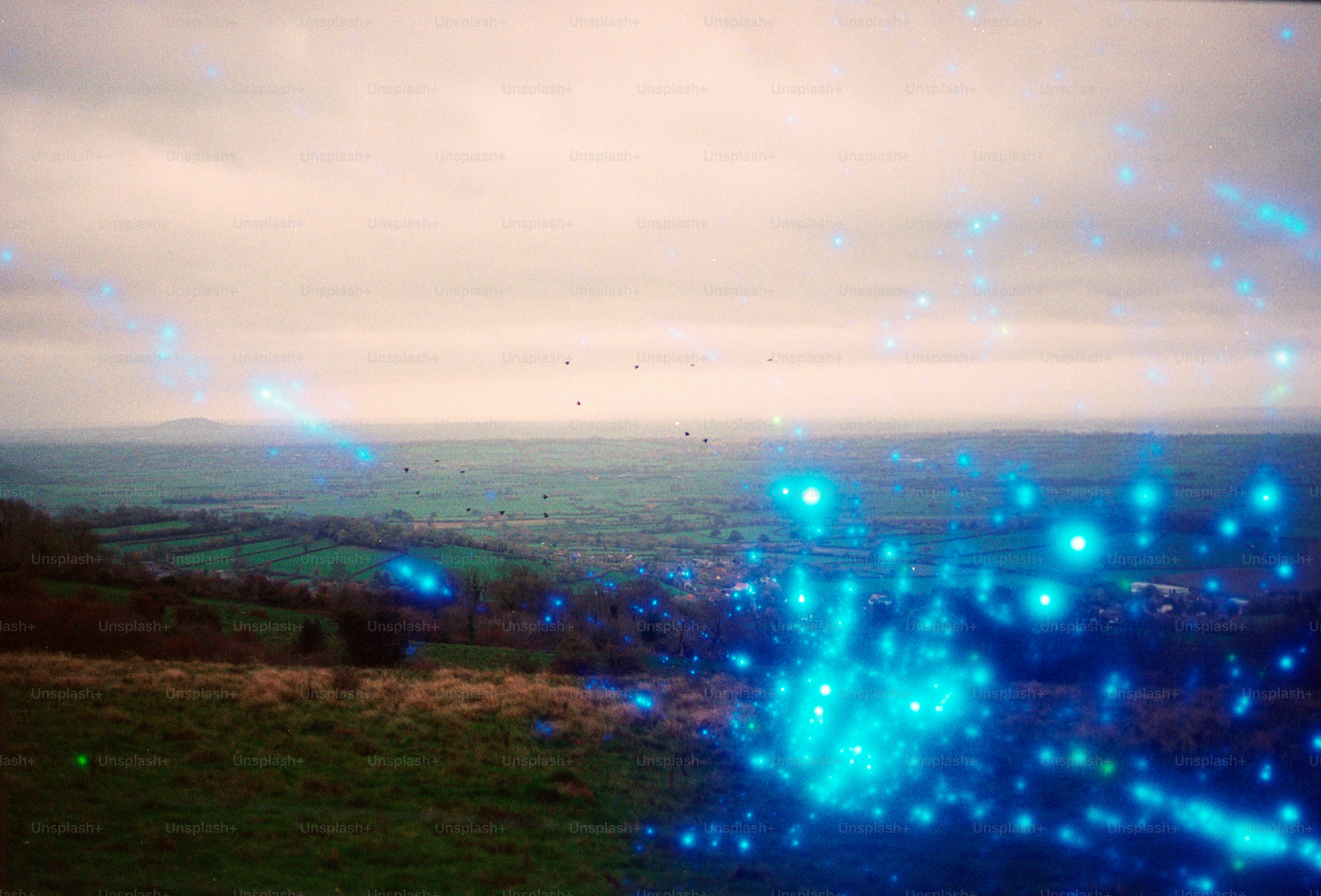 Blue lights float over a rolling green landscape.