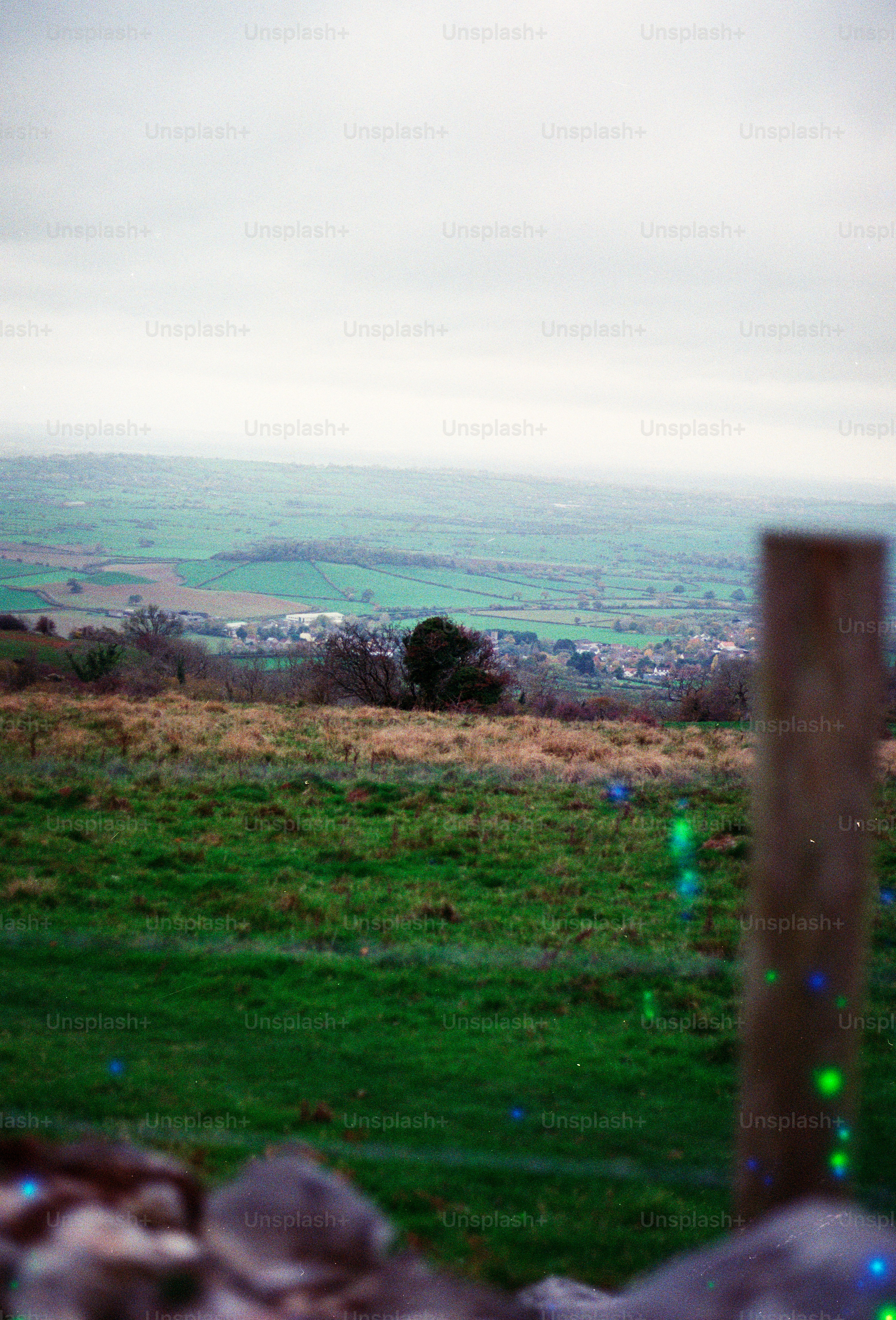Green rolling hills with a wooden fence post.