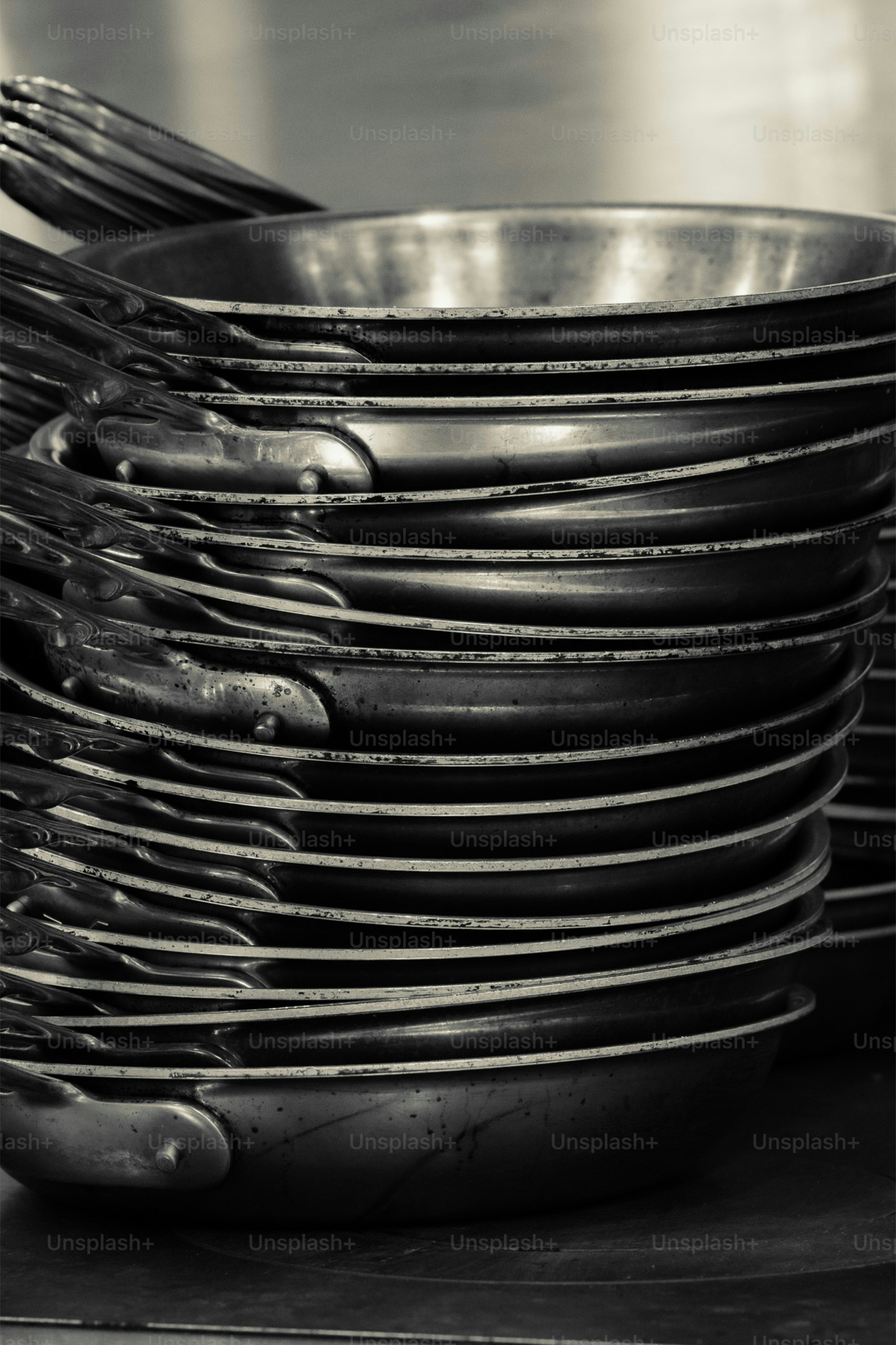 Ein Stapel Bratpfannen aus Metall in einer Küche.