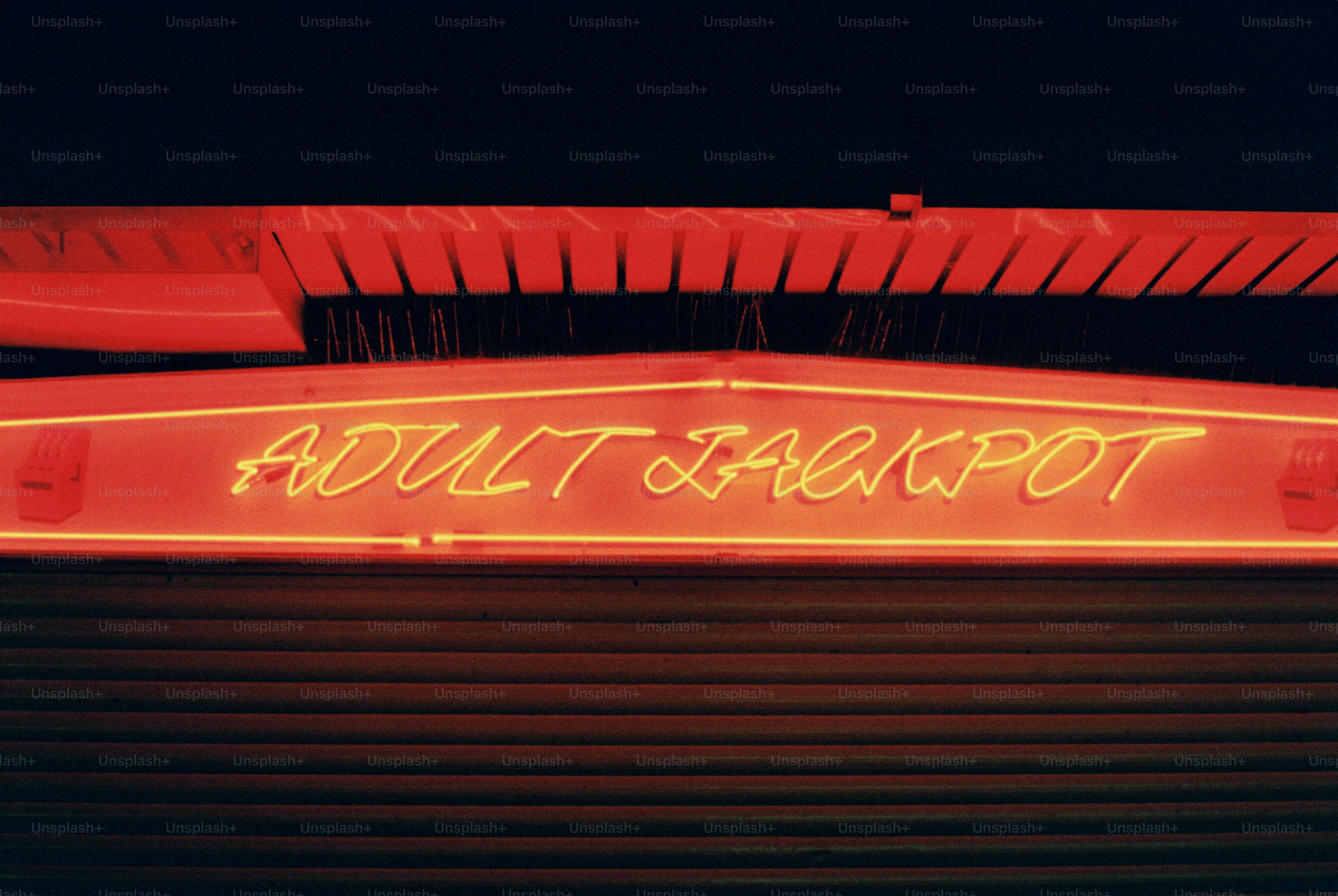 Neon sign reads "adult jackpot" at night.
