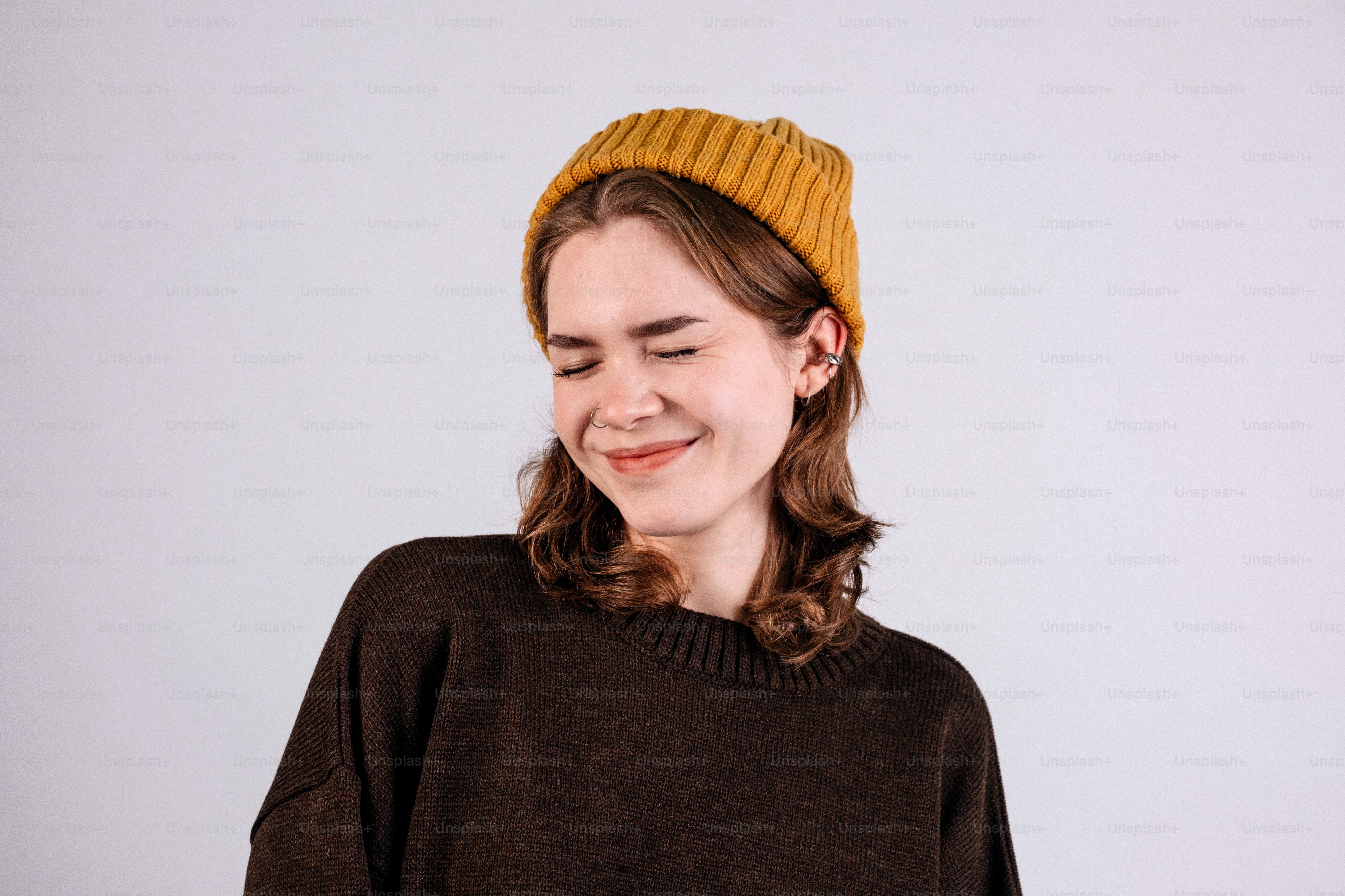 Young woman wearing a mustard beanie and brown sweater