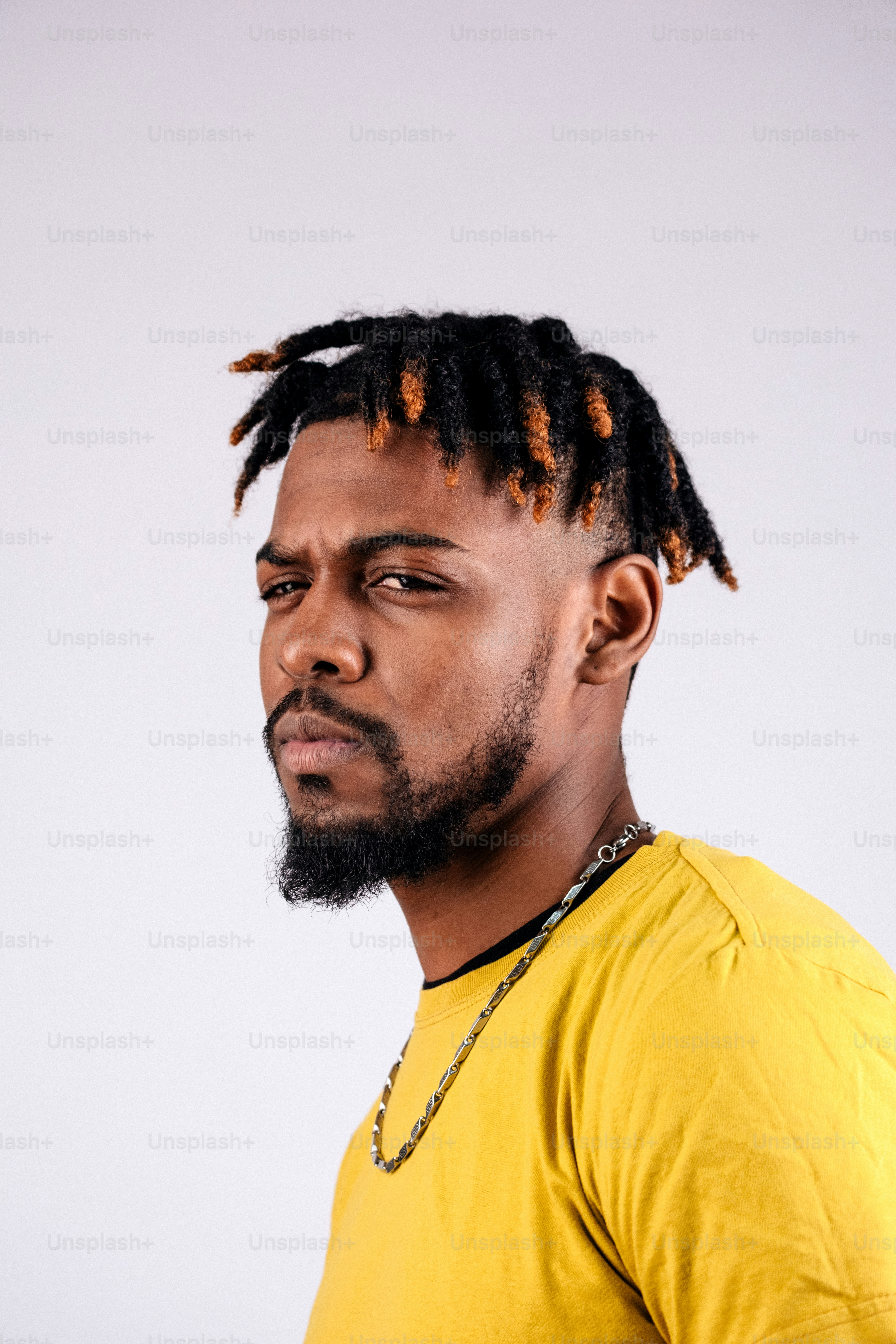 Man with dreadlocks and beard wearing yellow shirt.
