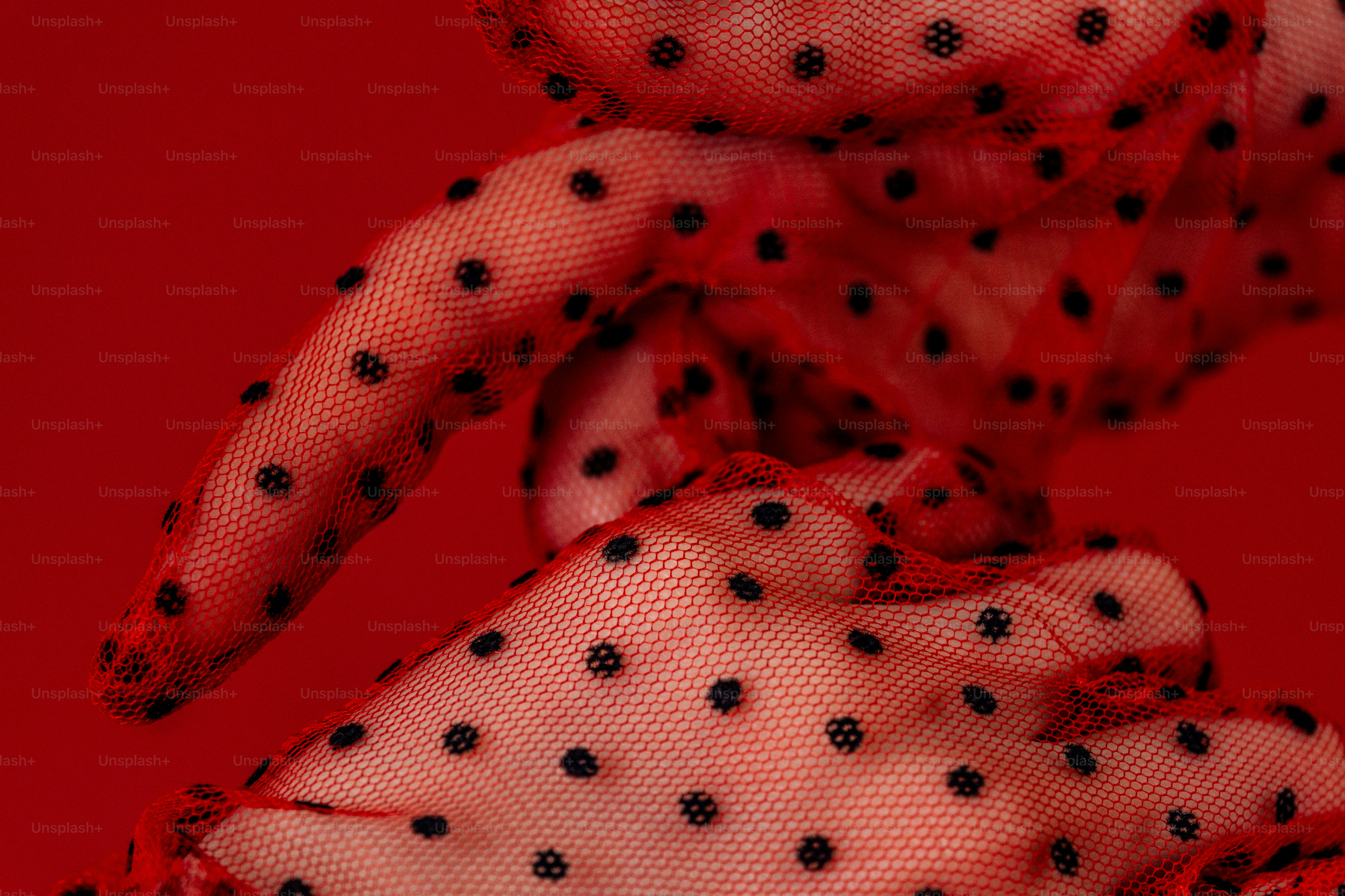 Roter transparenter Stoff mit schwarzen Punkten an den Händen