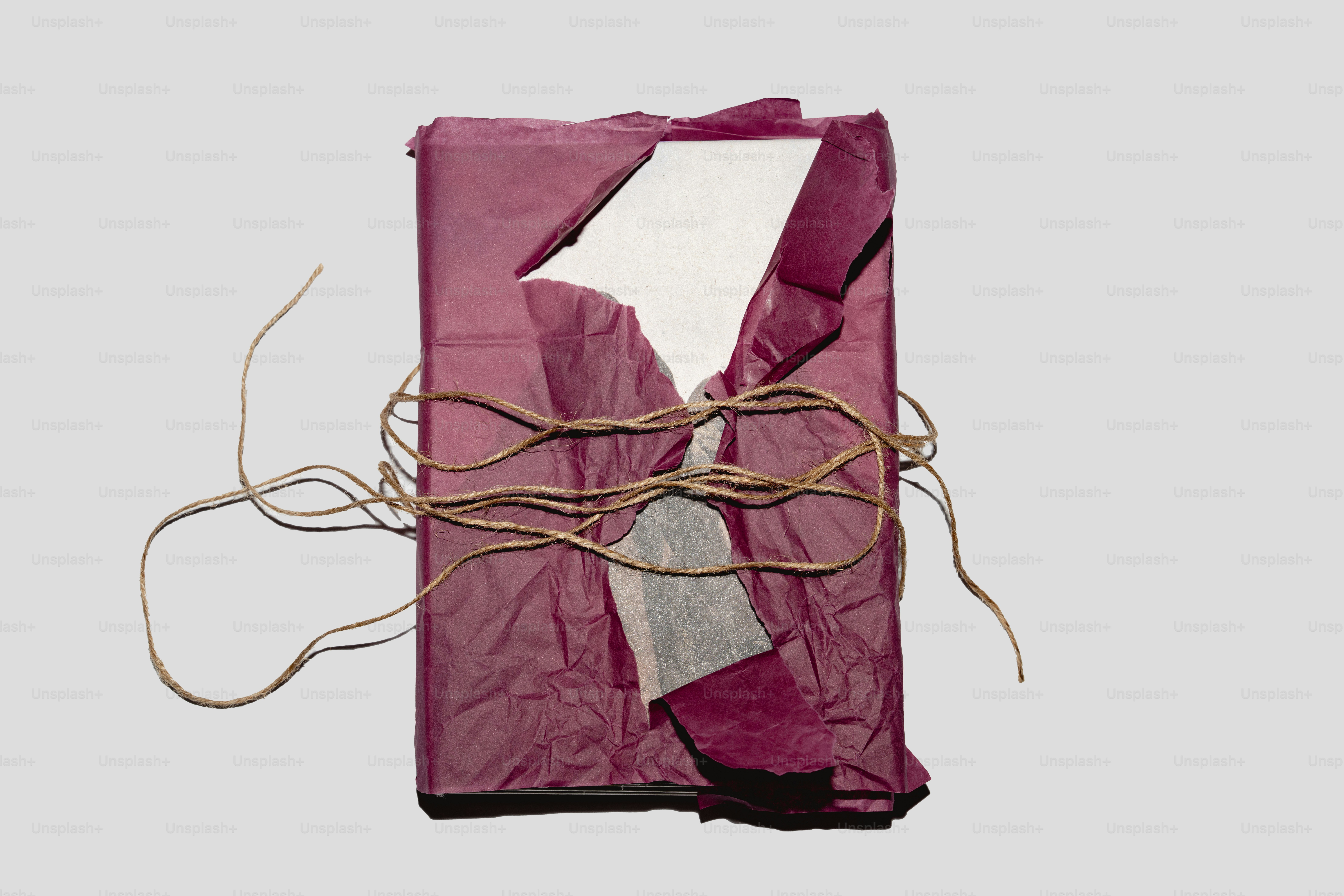 A gift wrapped in torn purple paper and twine.