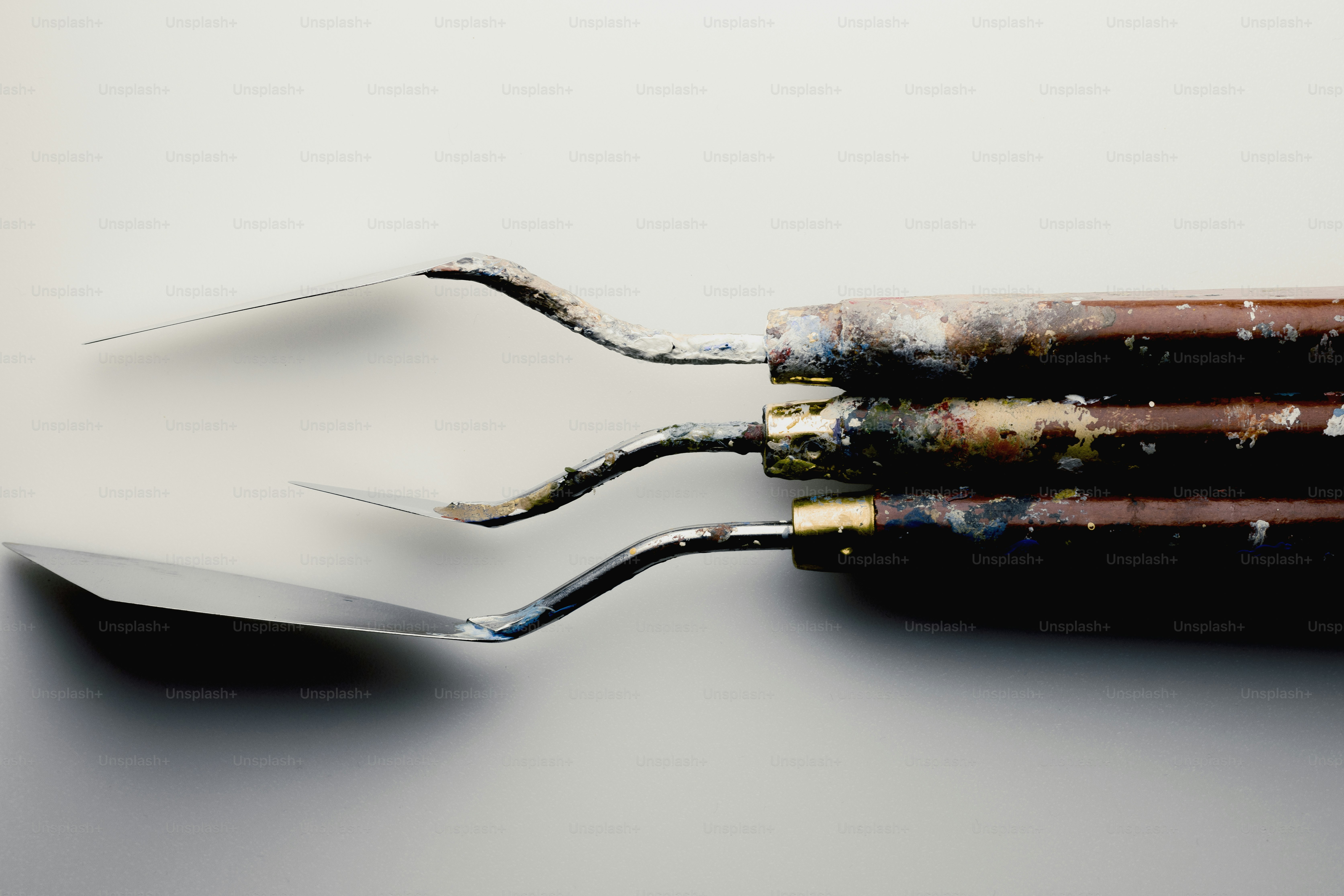 Three art palette knives on a light background
