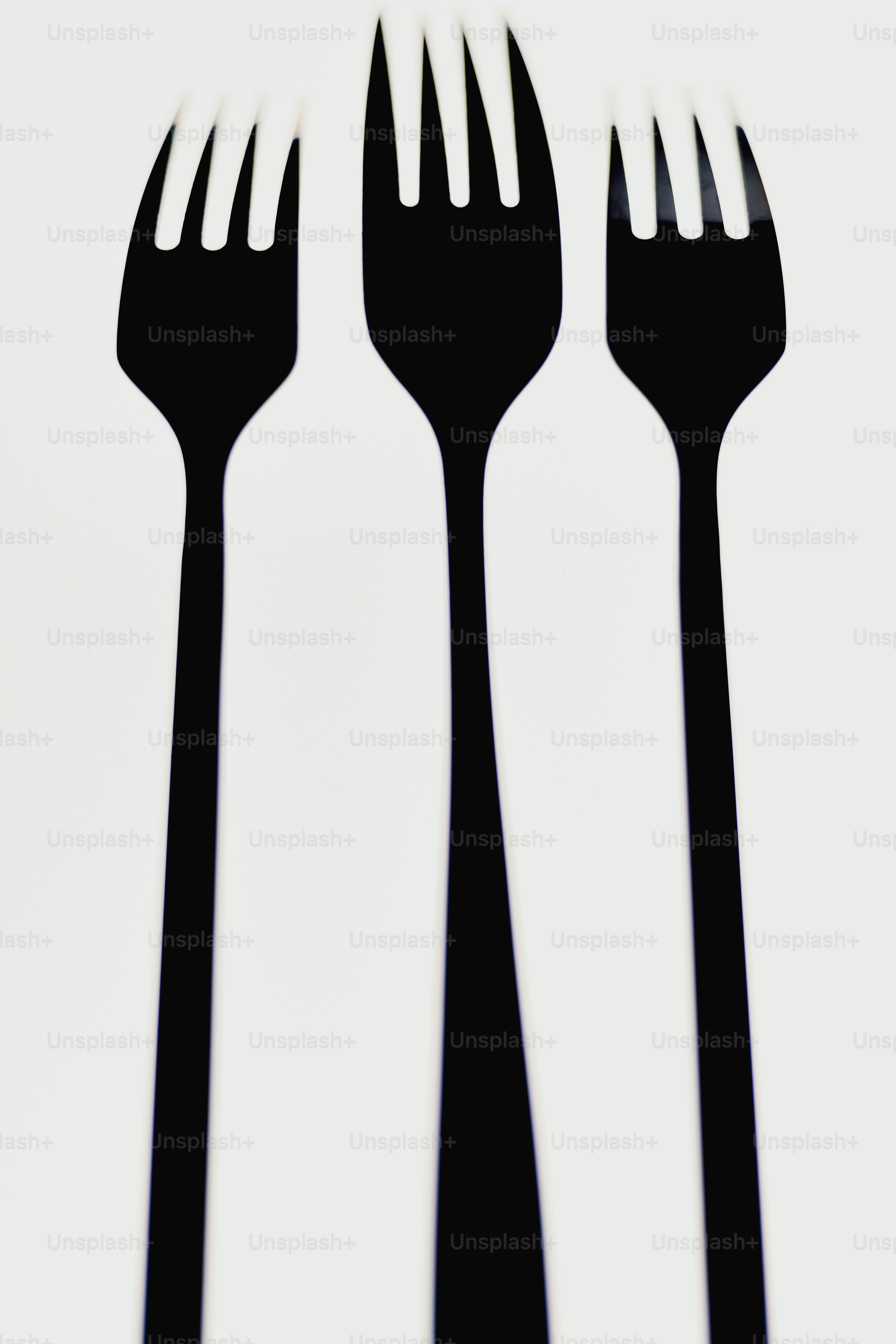 Three black forks arranged vertically on white background photo ...