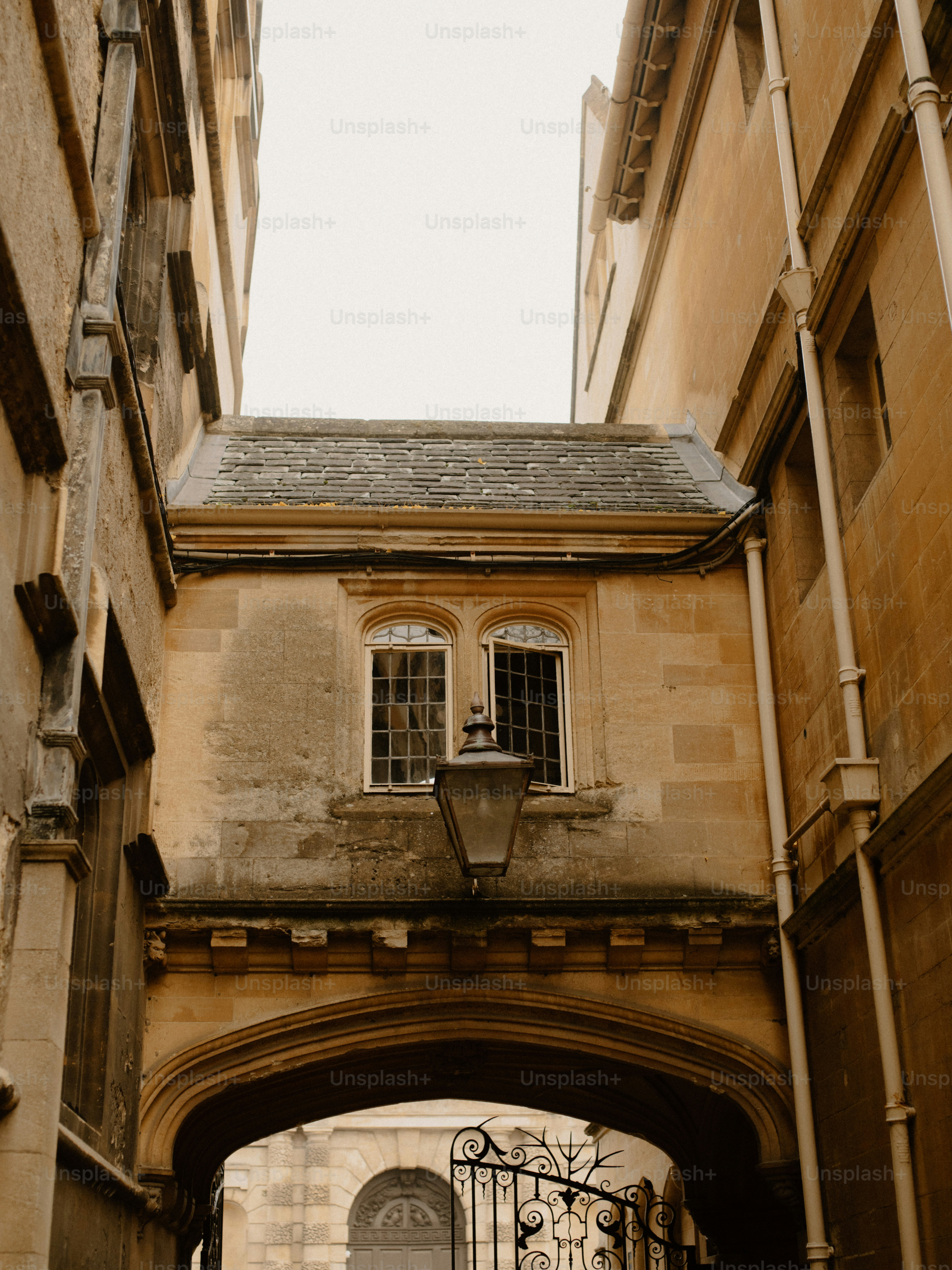 Arco de pedra entre prédios antigos com lanterna.