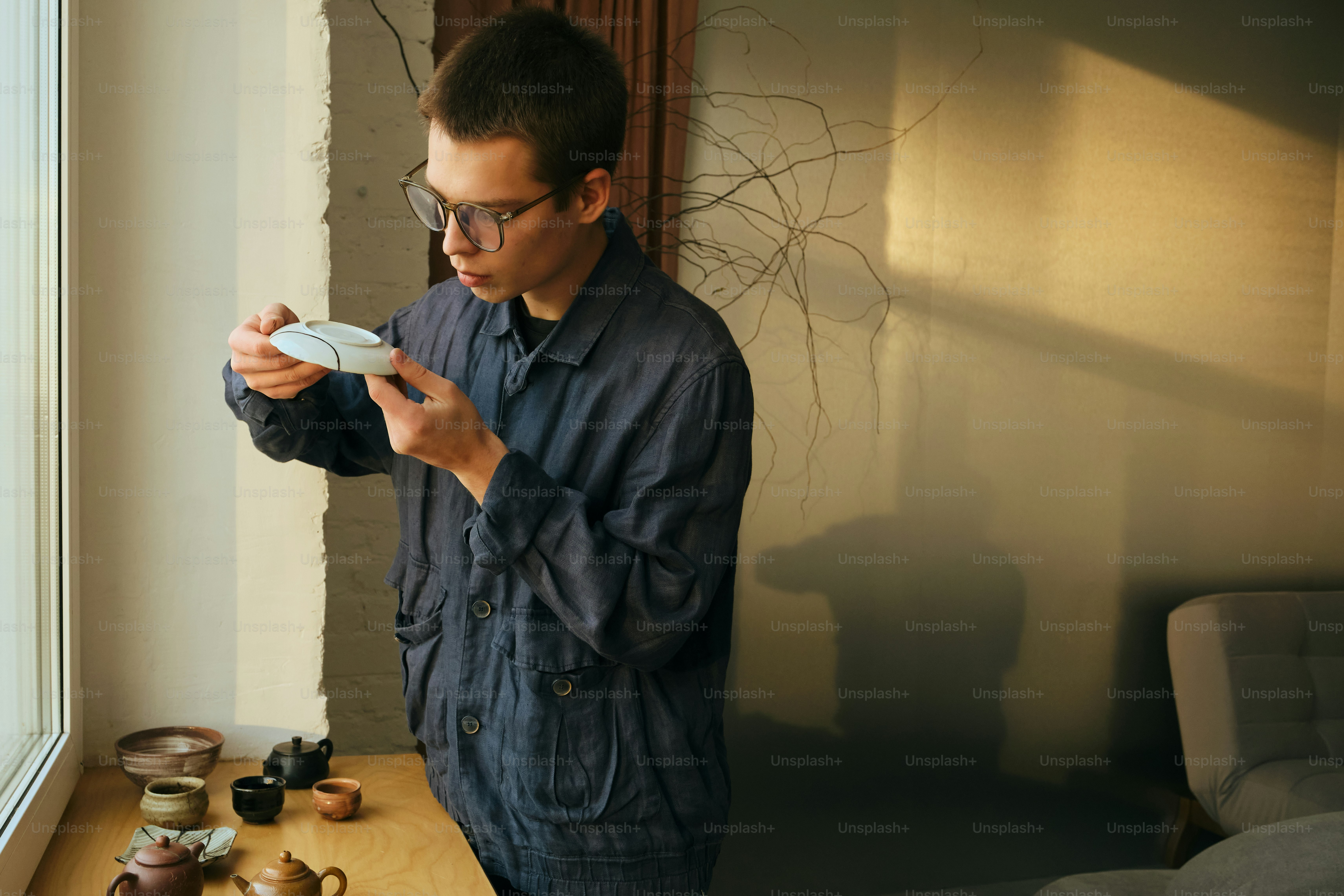 Man examining a small white teacup by window