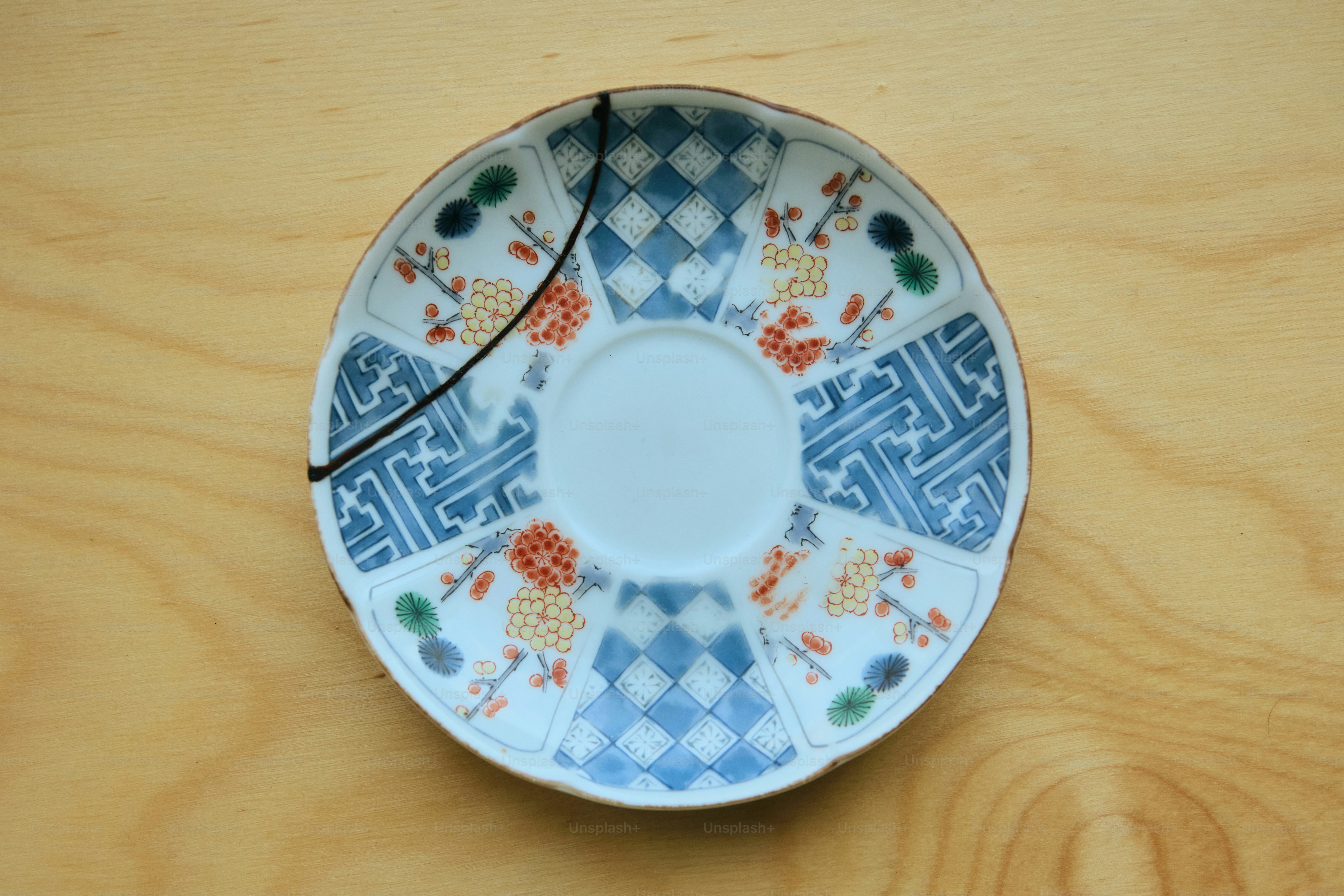 A cracked decorative plate with blue and orange patterns