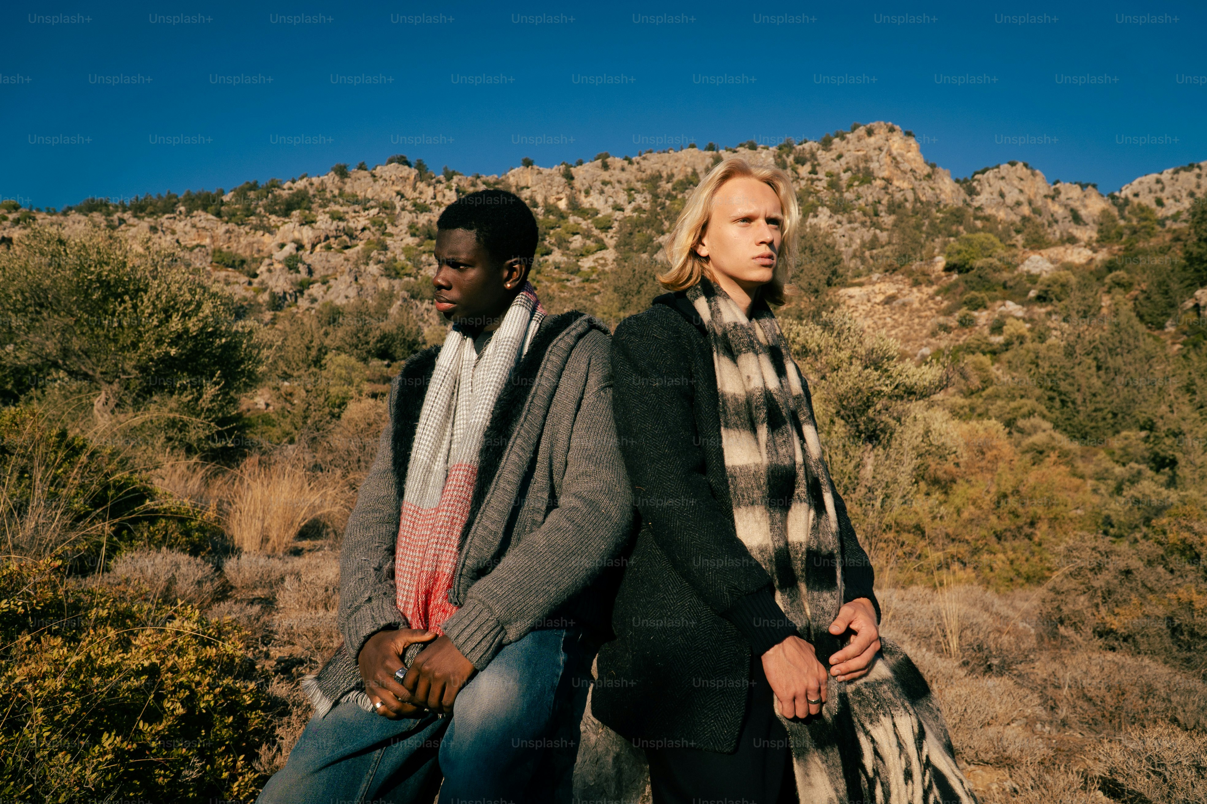 Two men sitting back to back outdoors