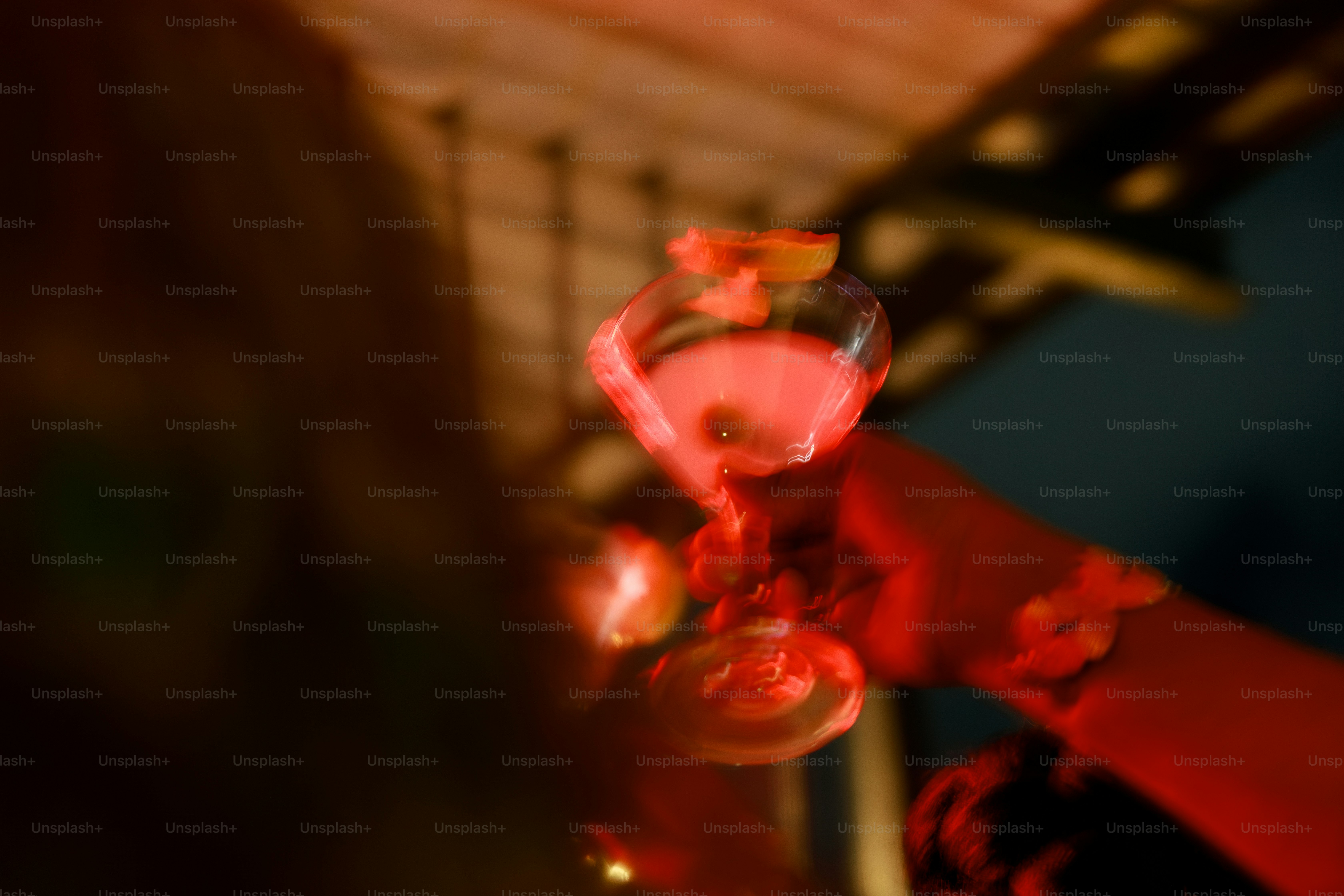 A hand holding a pink cocktail with a lime garnish.