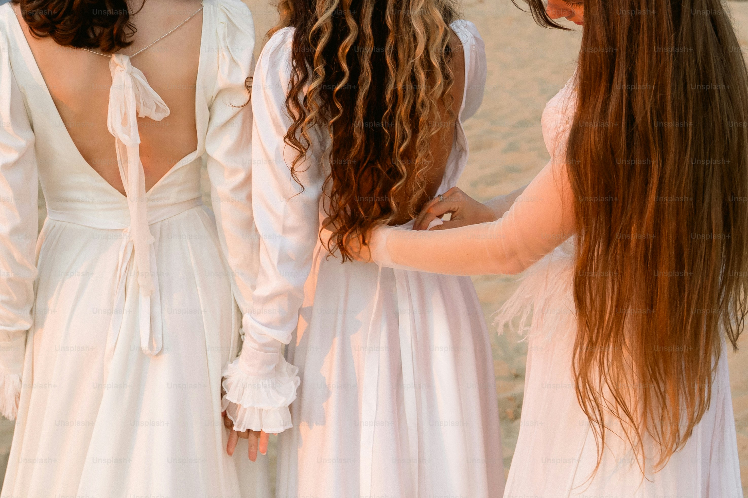Three women in white dresses on a beach