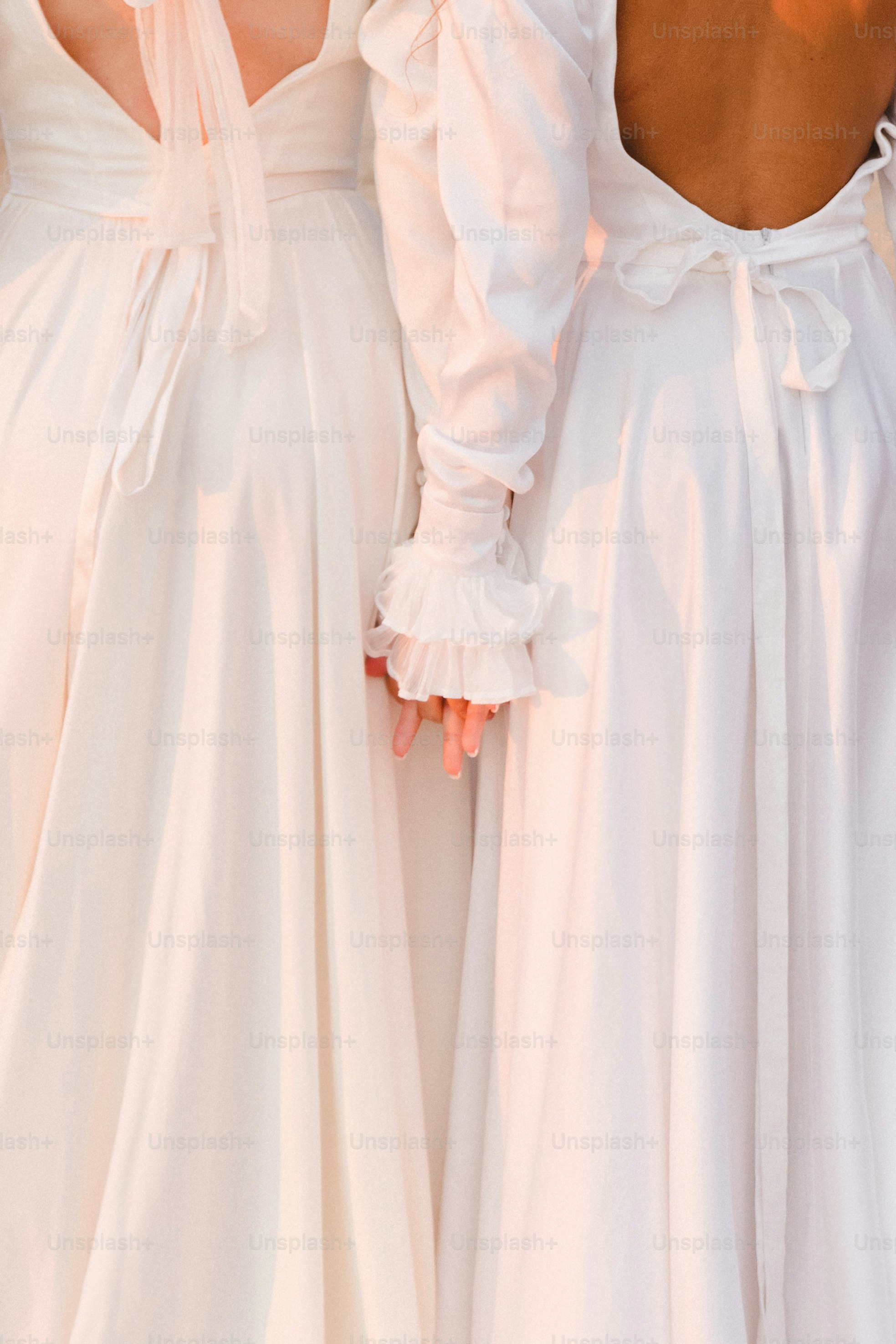 Two women in white dresses holding hands photo – Fashion Image on Unsplash