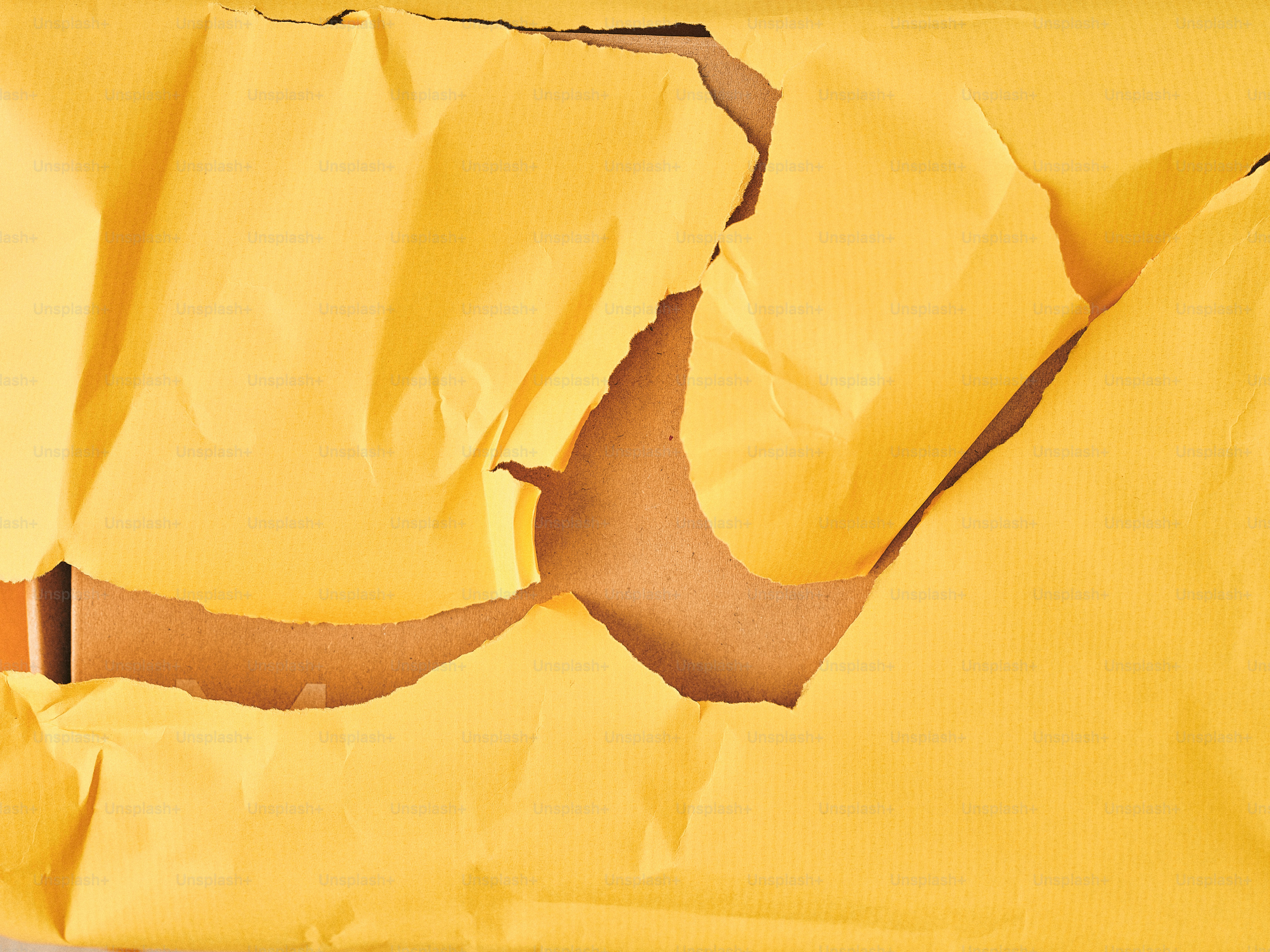 Torn yellow paper revealing cardboard underneath