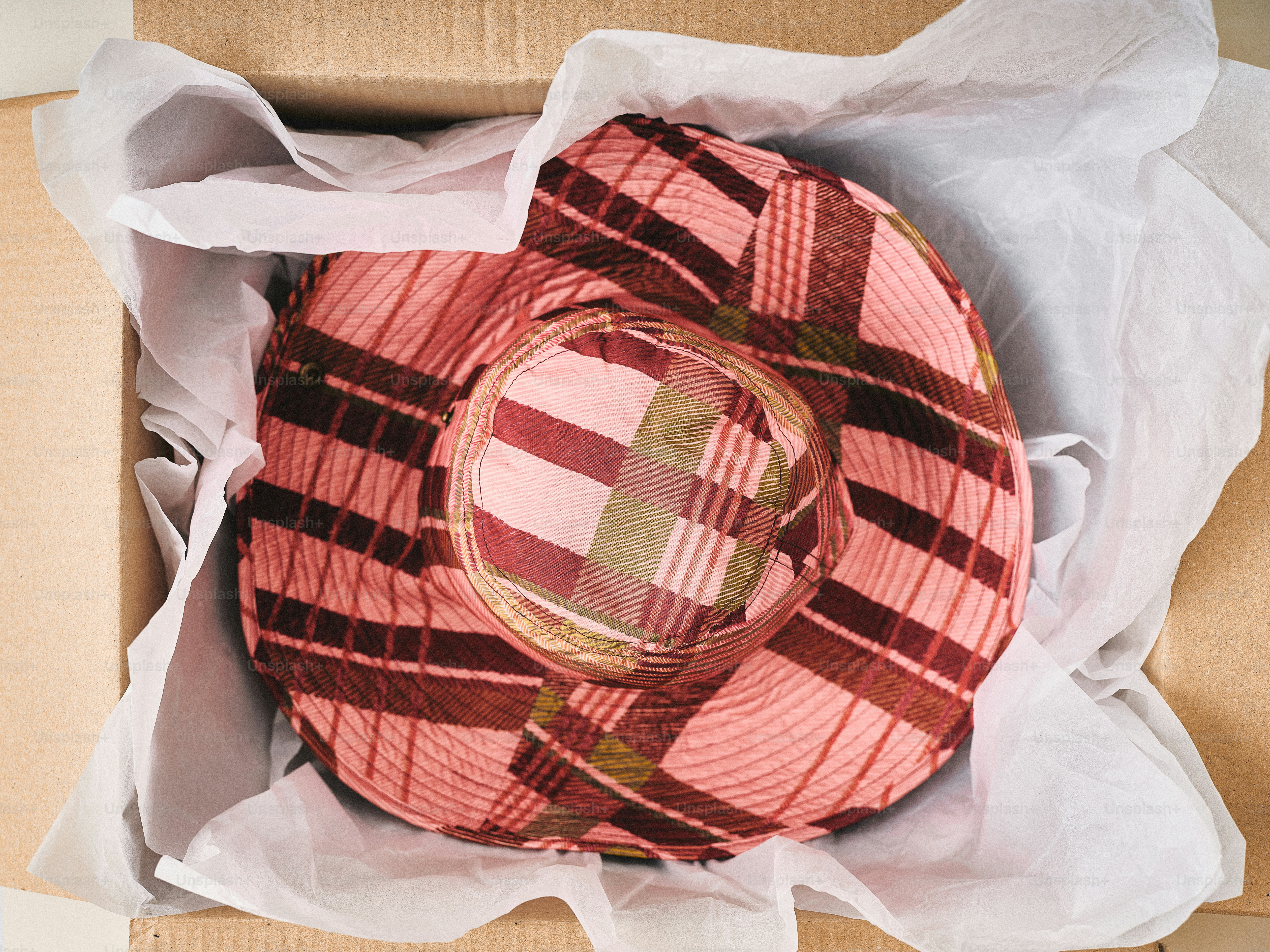 A pink plaid hat packed in a box