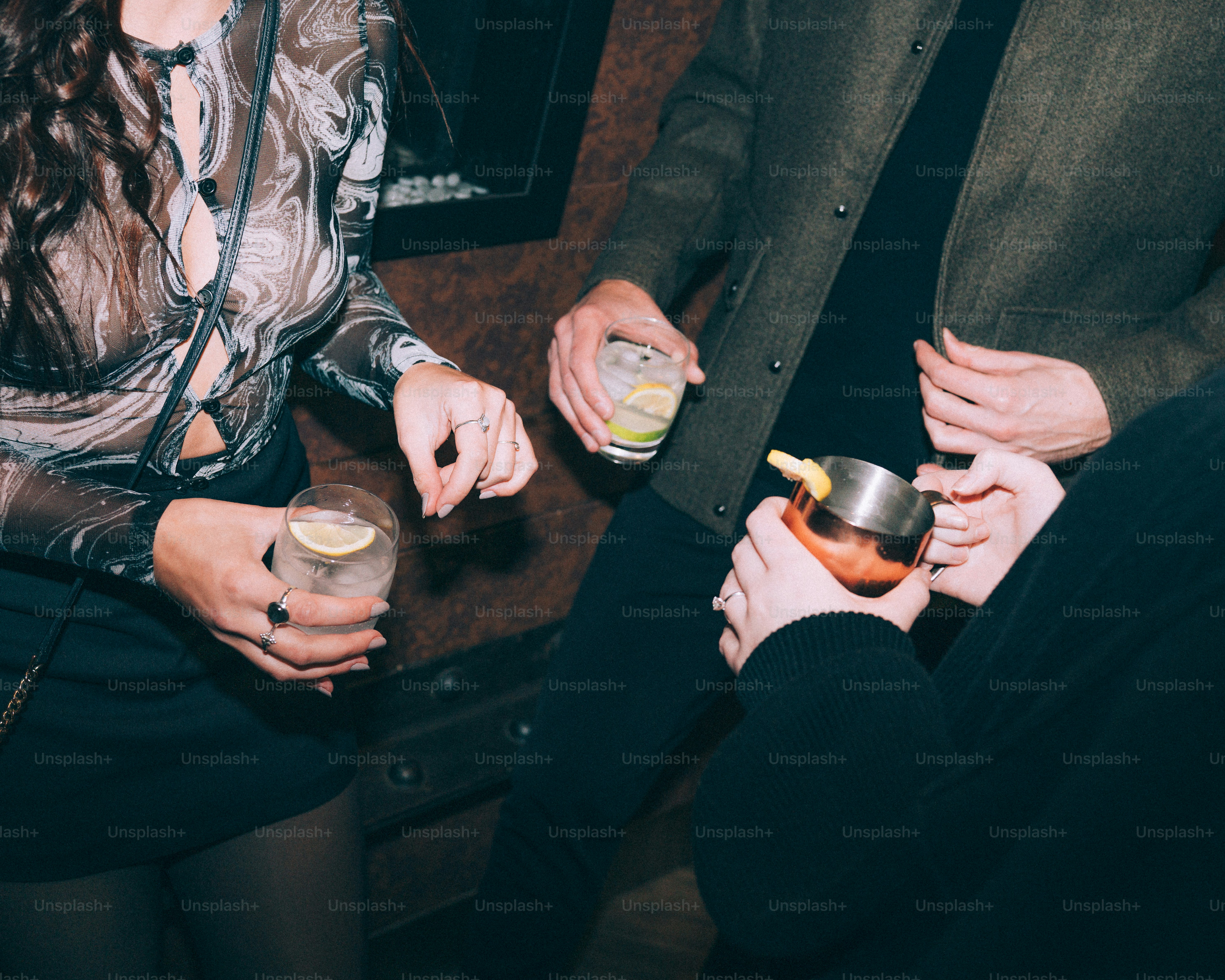 People holding cocktails at a bar