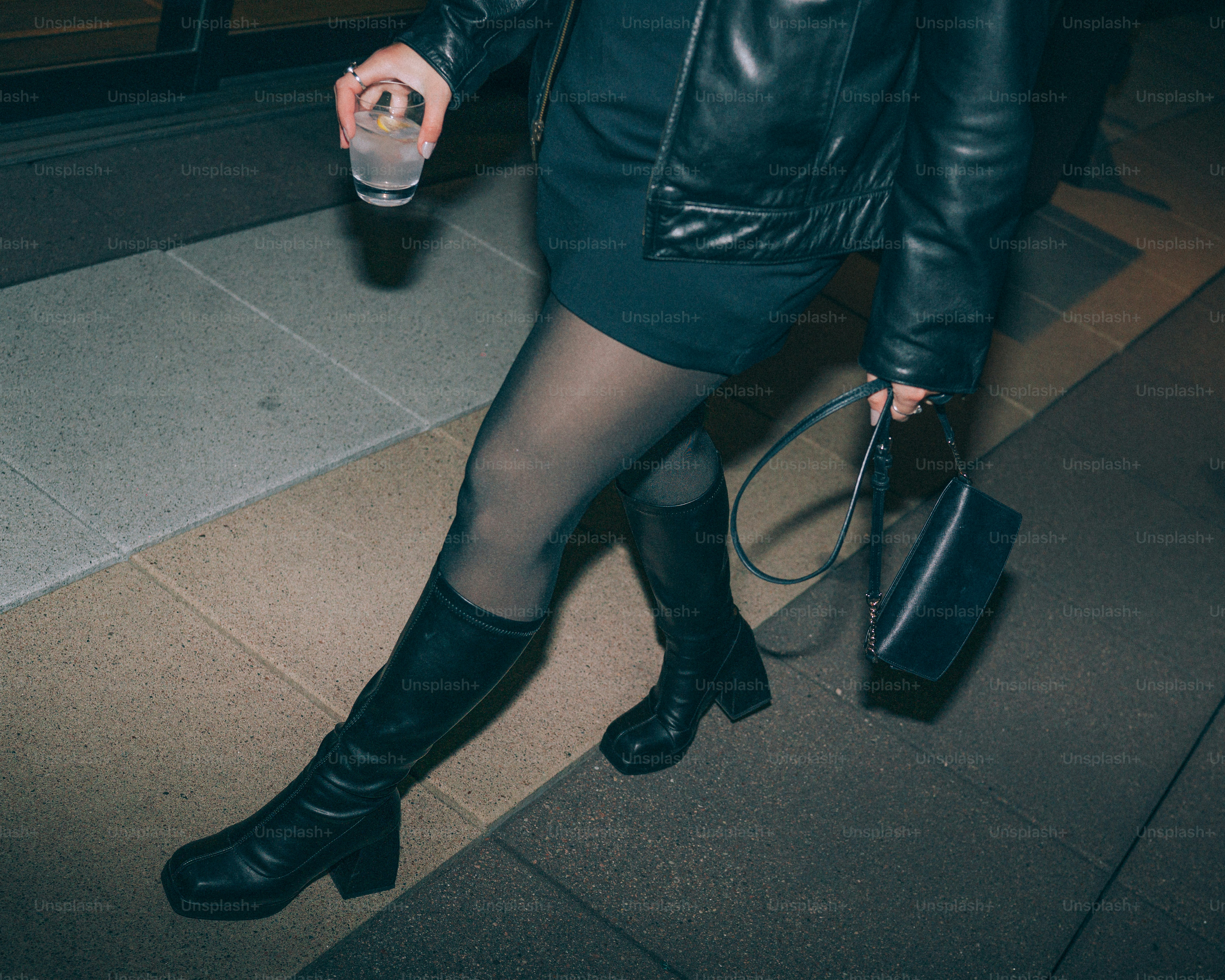 Woman in black dress and boots walking at night