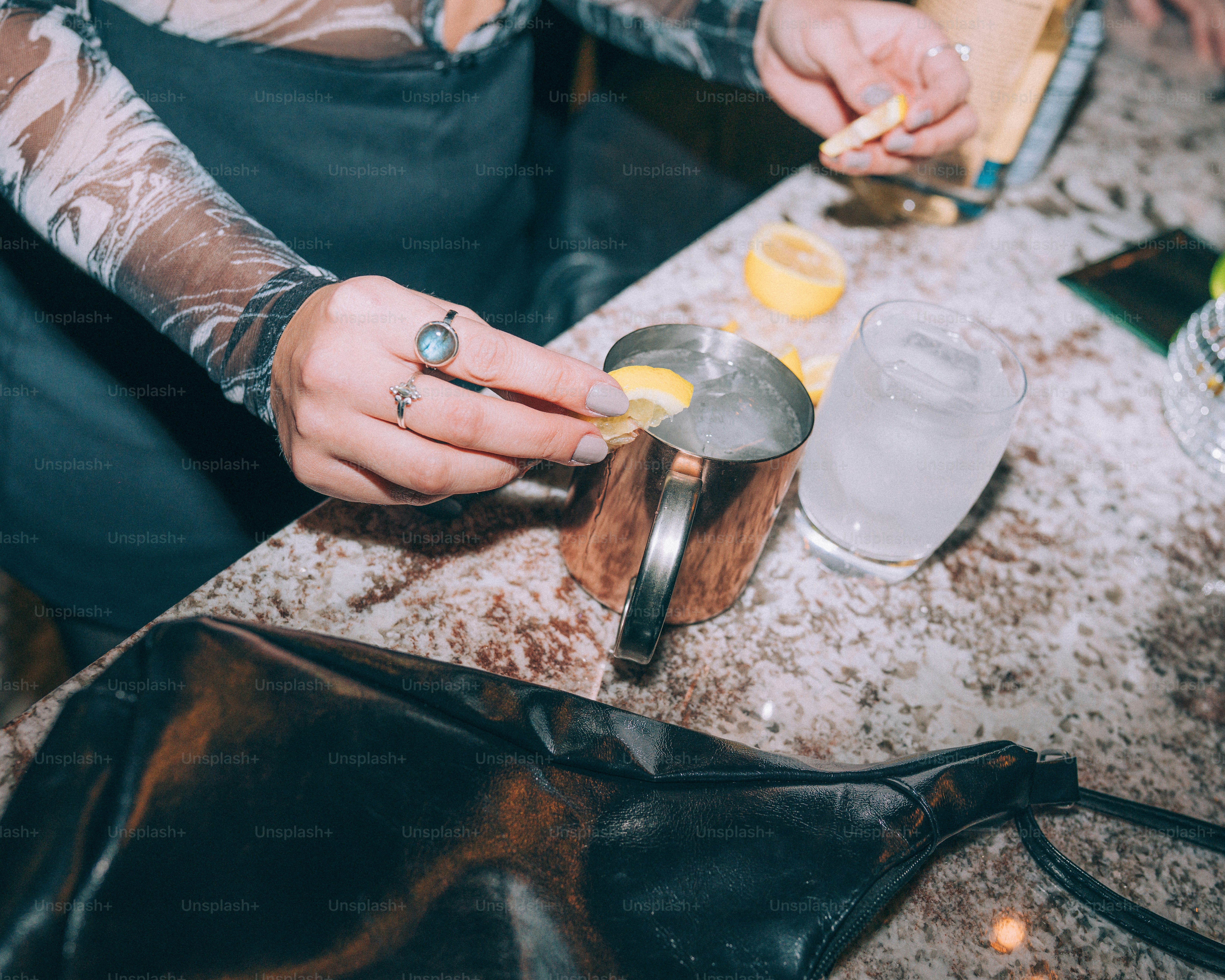 Hands adding lemon slice to copper mug drink