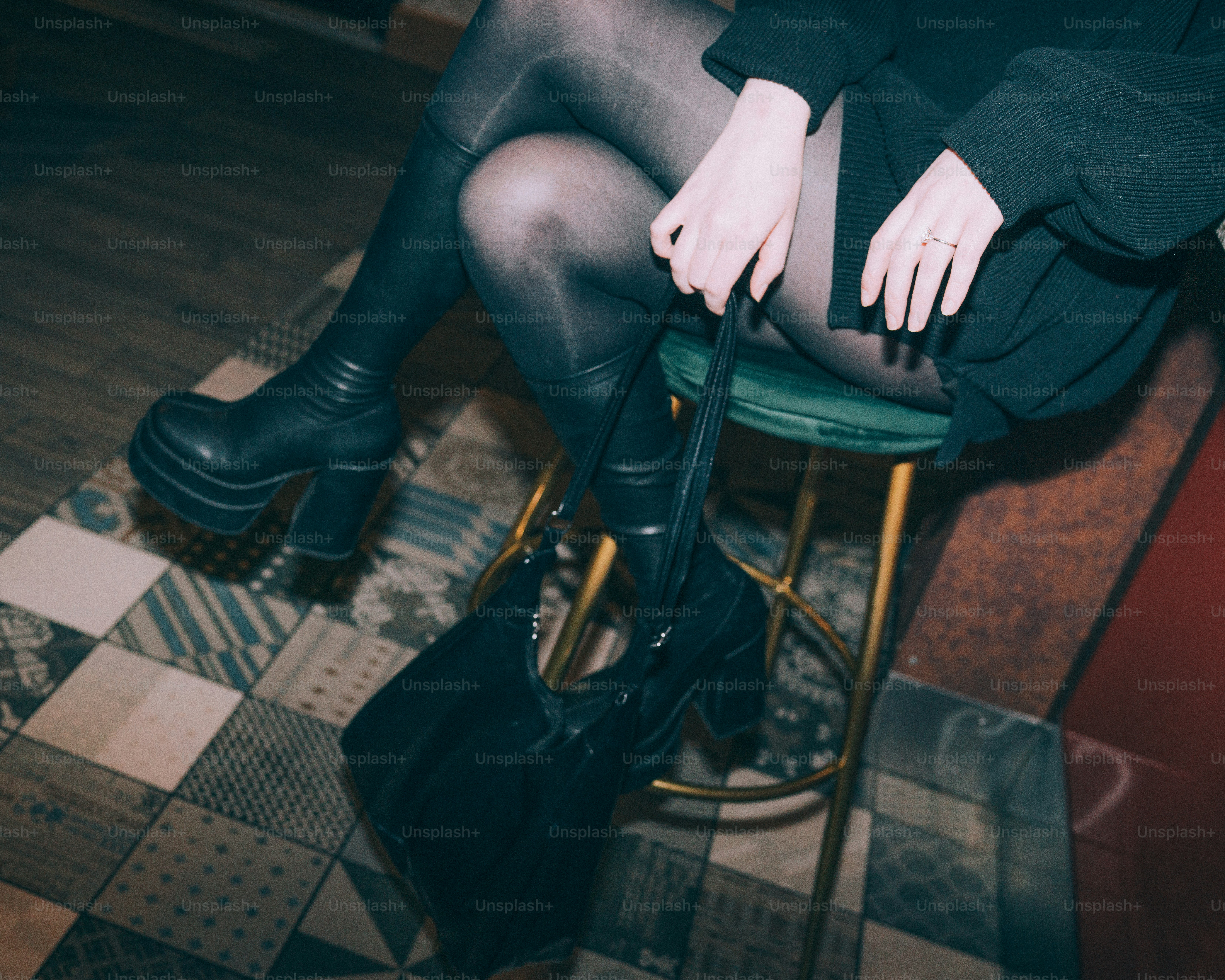 Woman in black boots holding handbag on stool