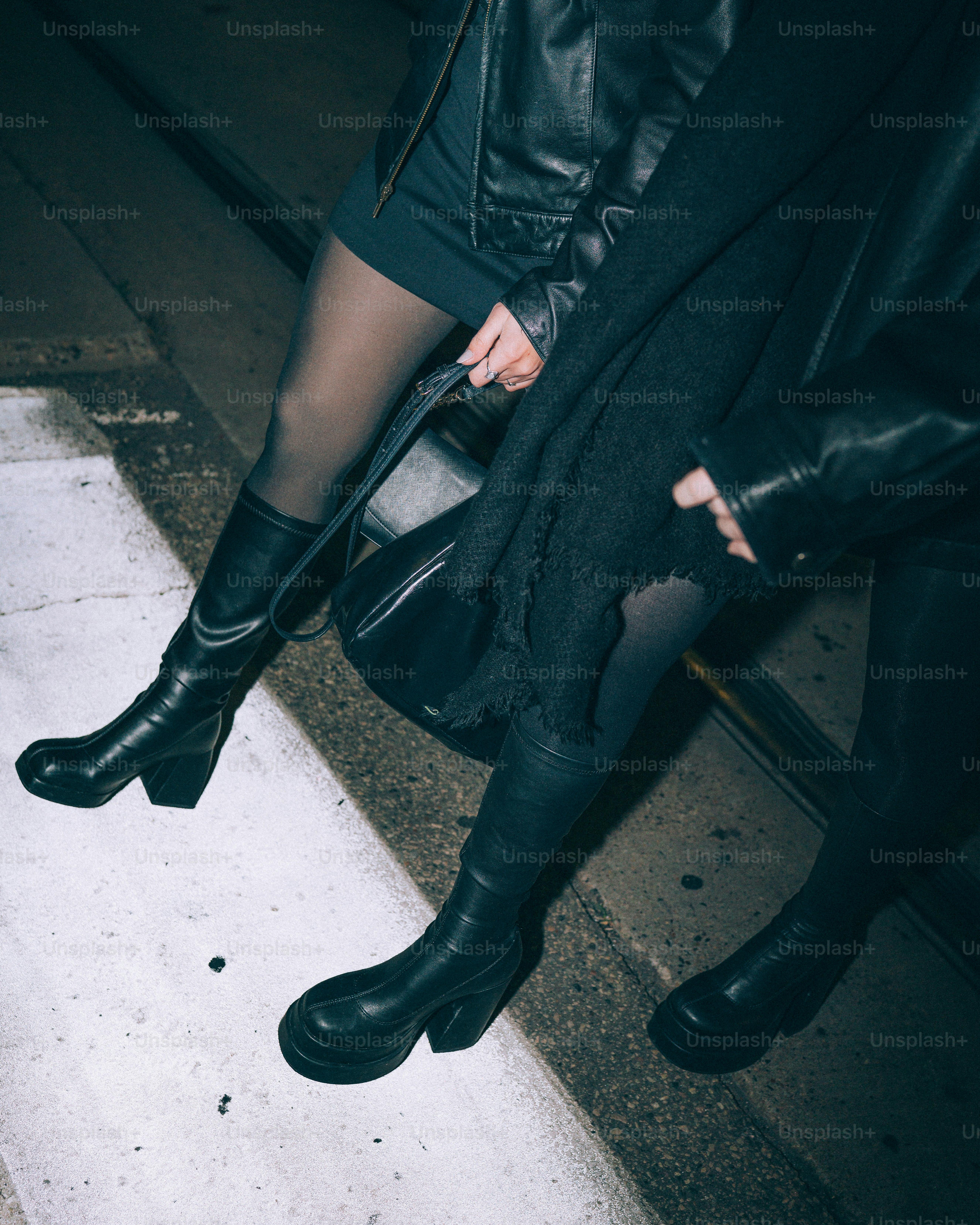Two people wearing black boots and dark clothing