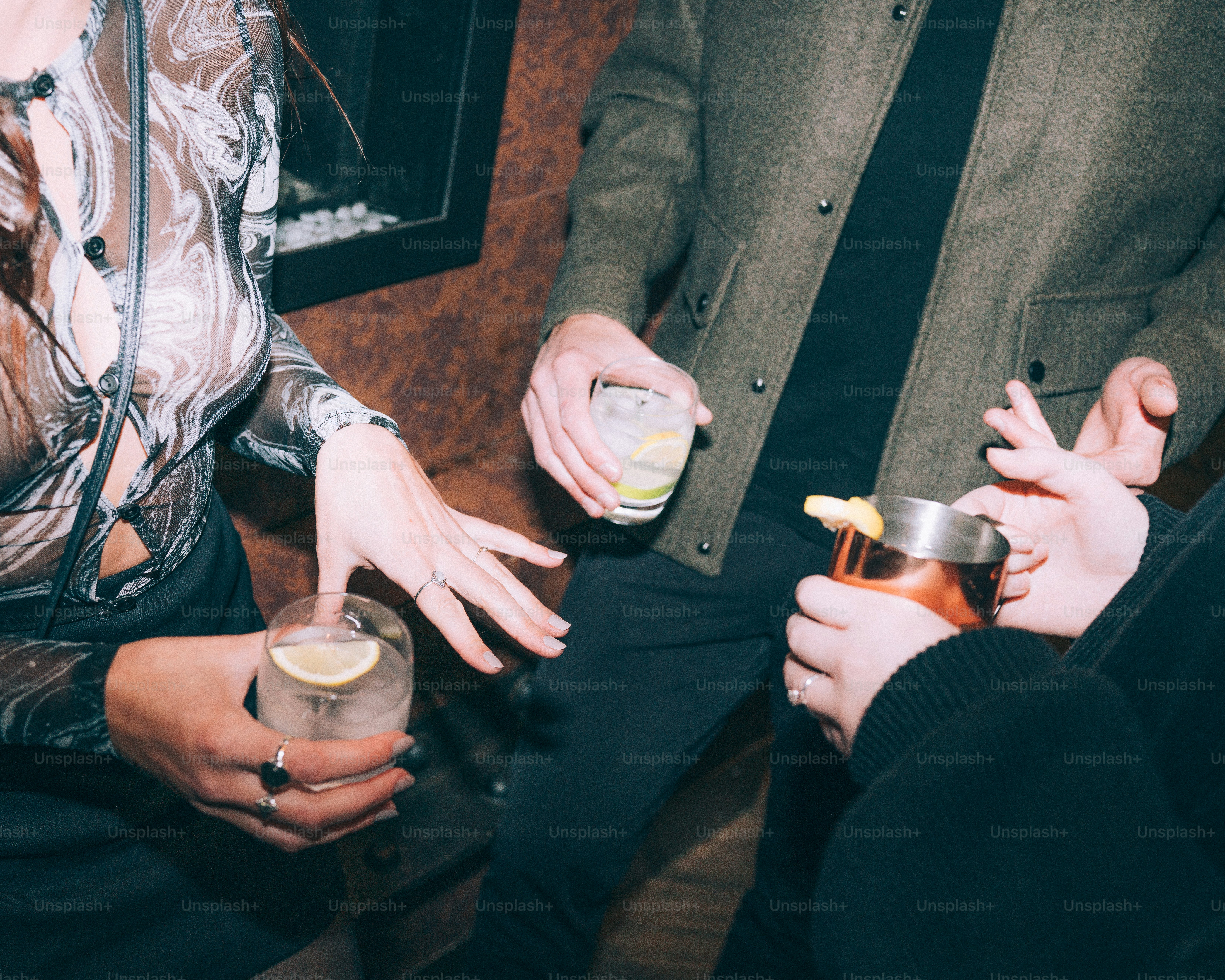 Friends holding cocktails at a dimly lit bar.
