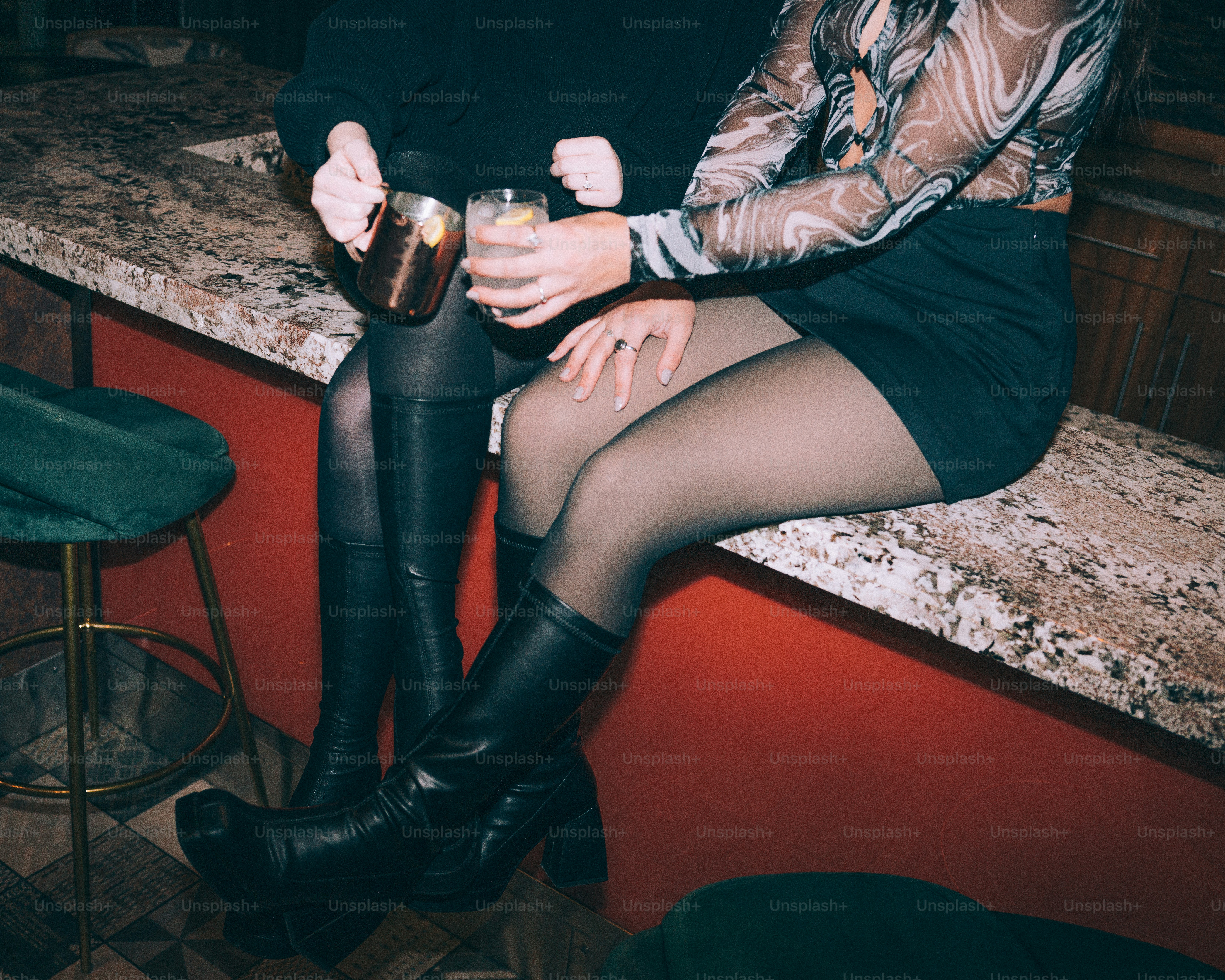 Two people sitting at a bar with drinks.