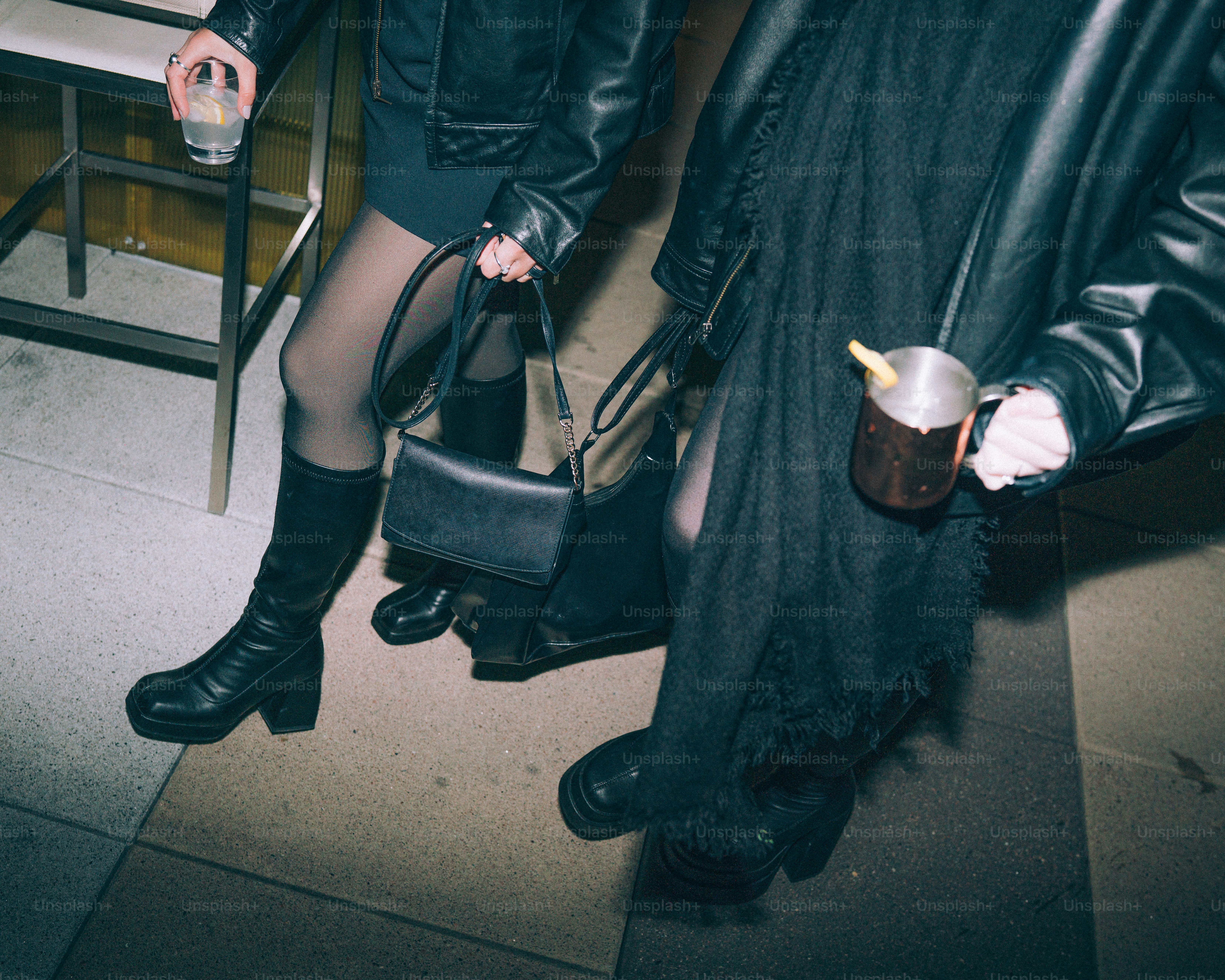 Two people in black leather jackets holding drinks.