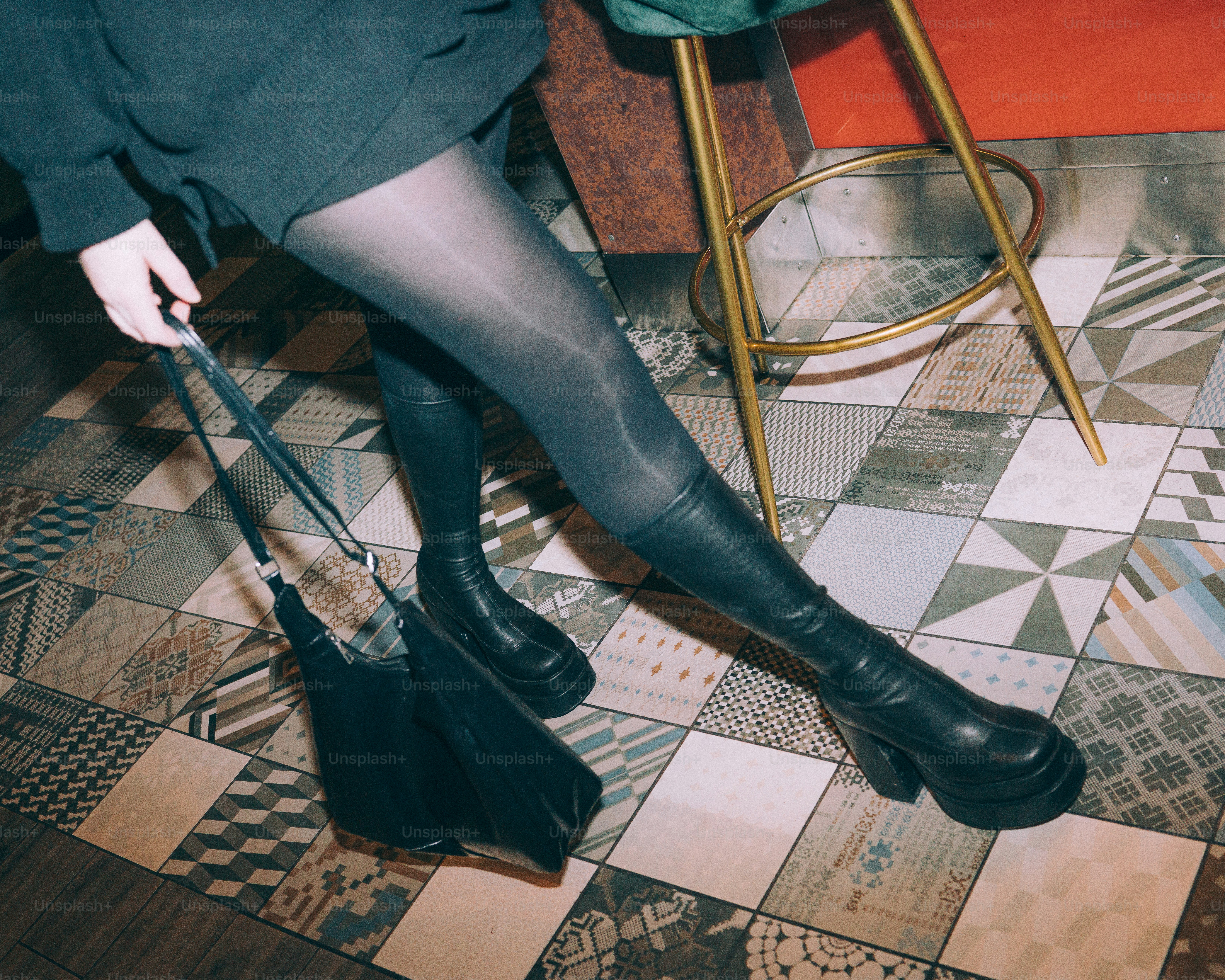 Woman in black boots and tights holding a purse.