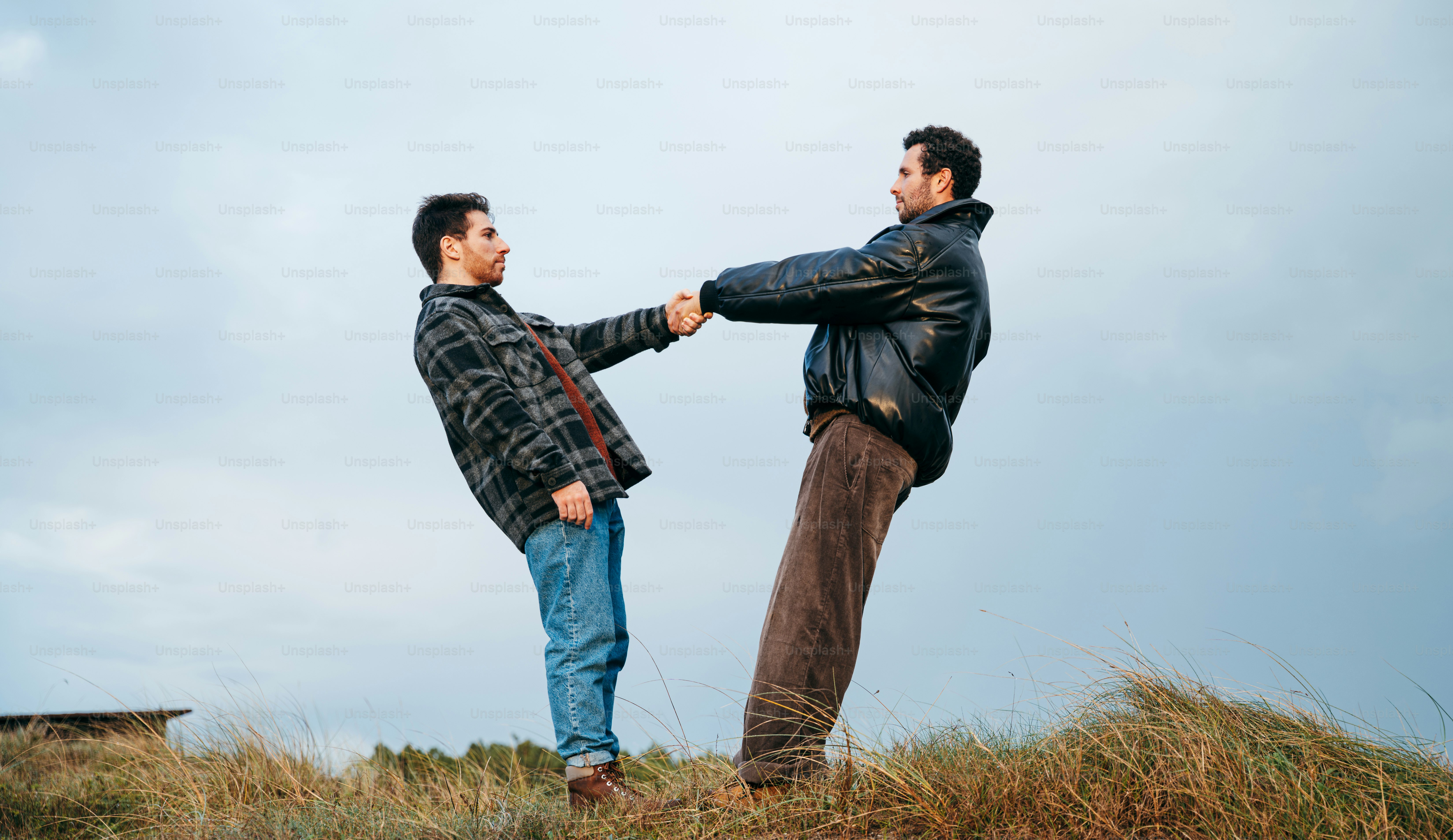 Two men holding hands, leaning against each other.