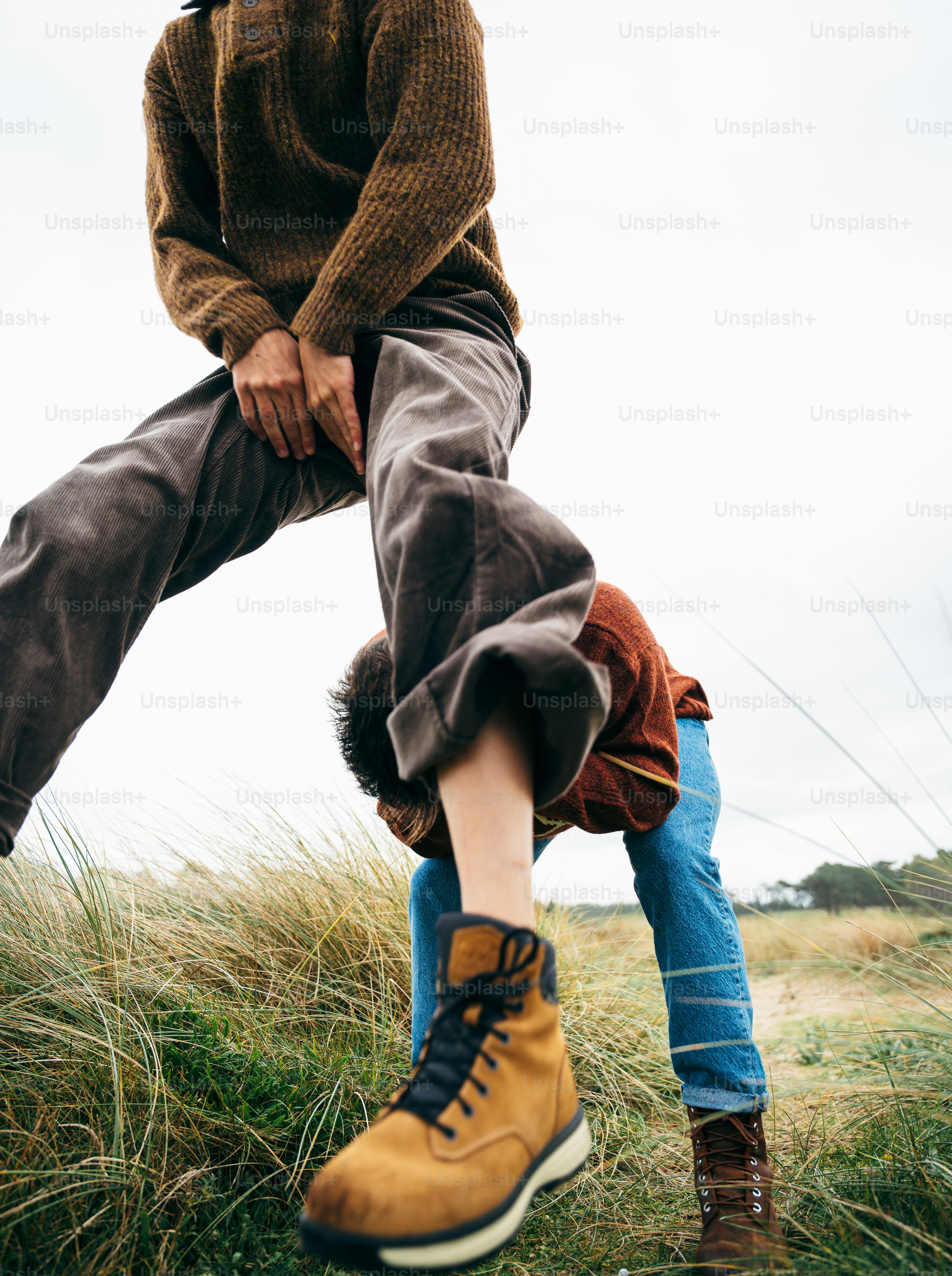 Two people walking through grassy dunes