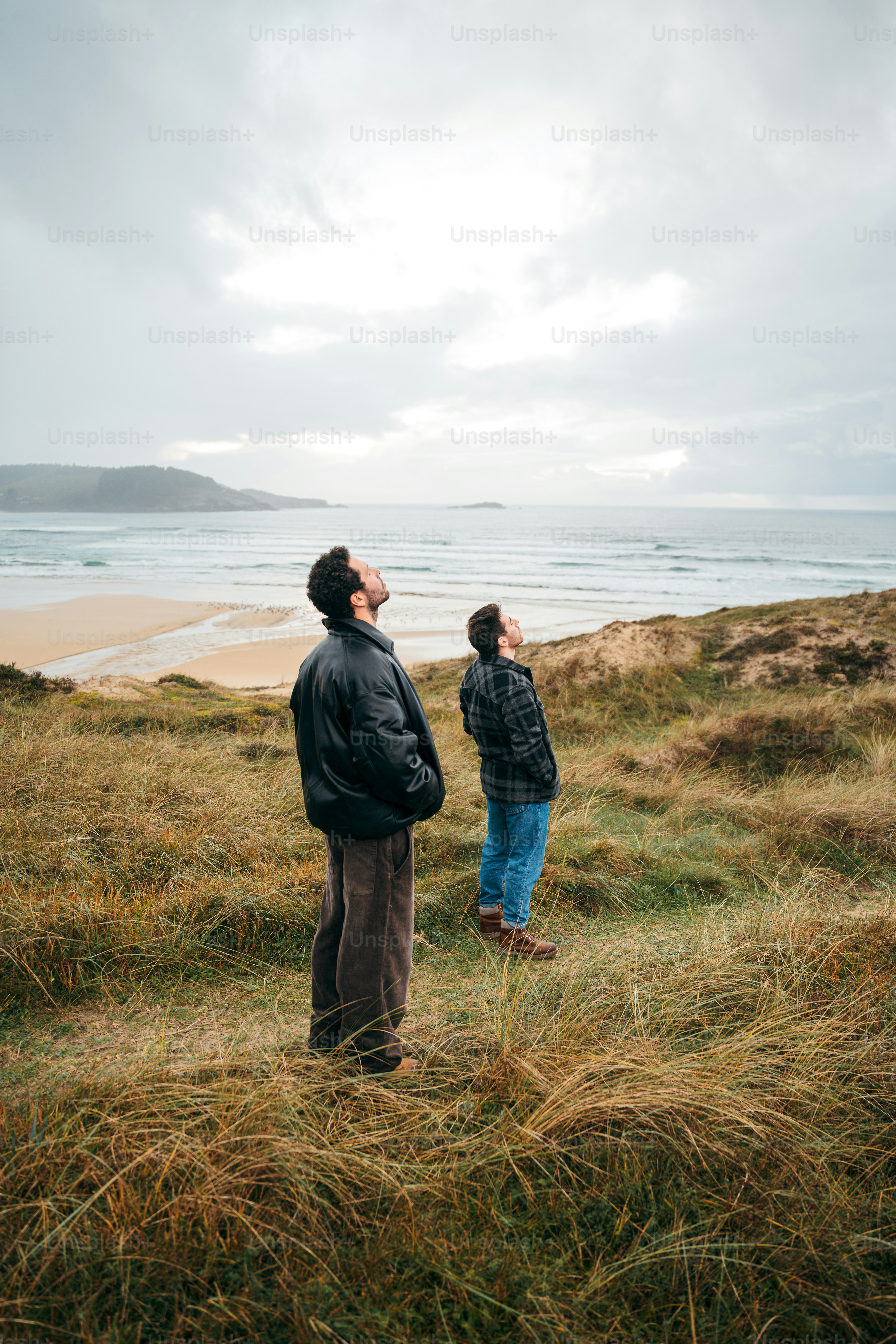 Two men looking up at the sky on a beach