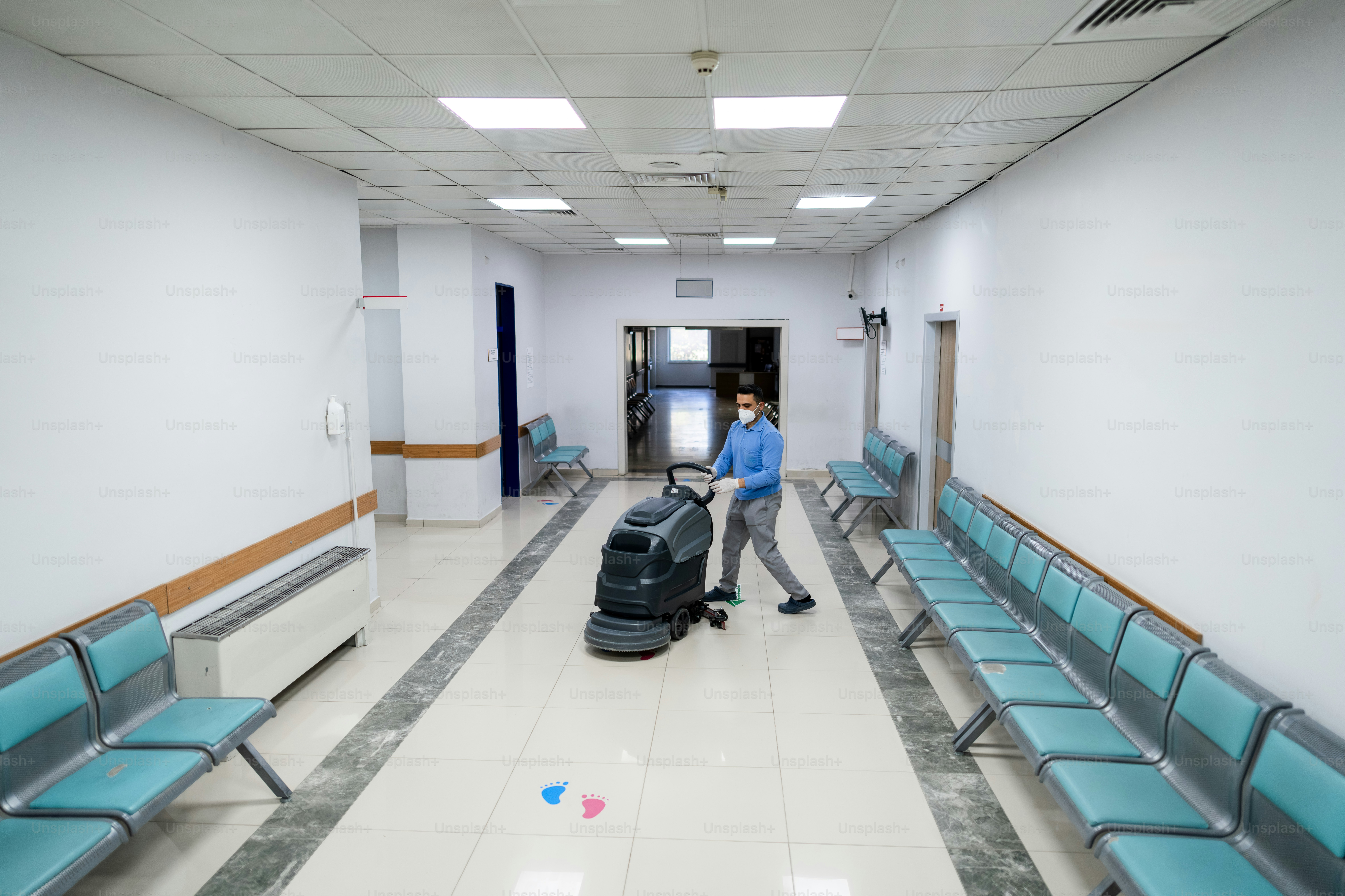 Man cleaning hallway floor with a machine