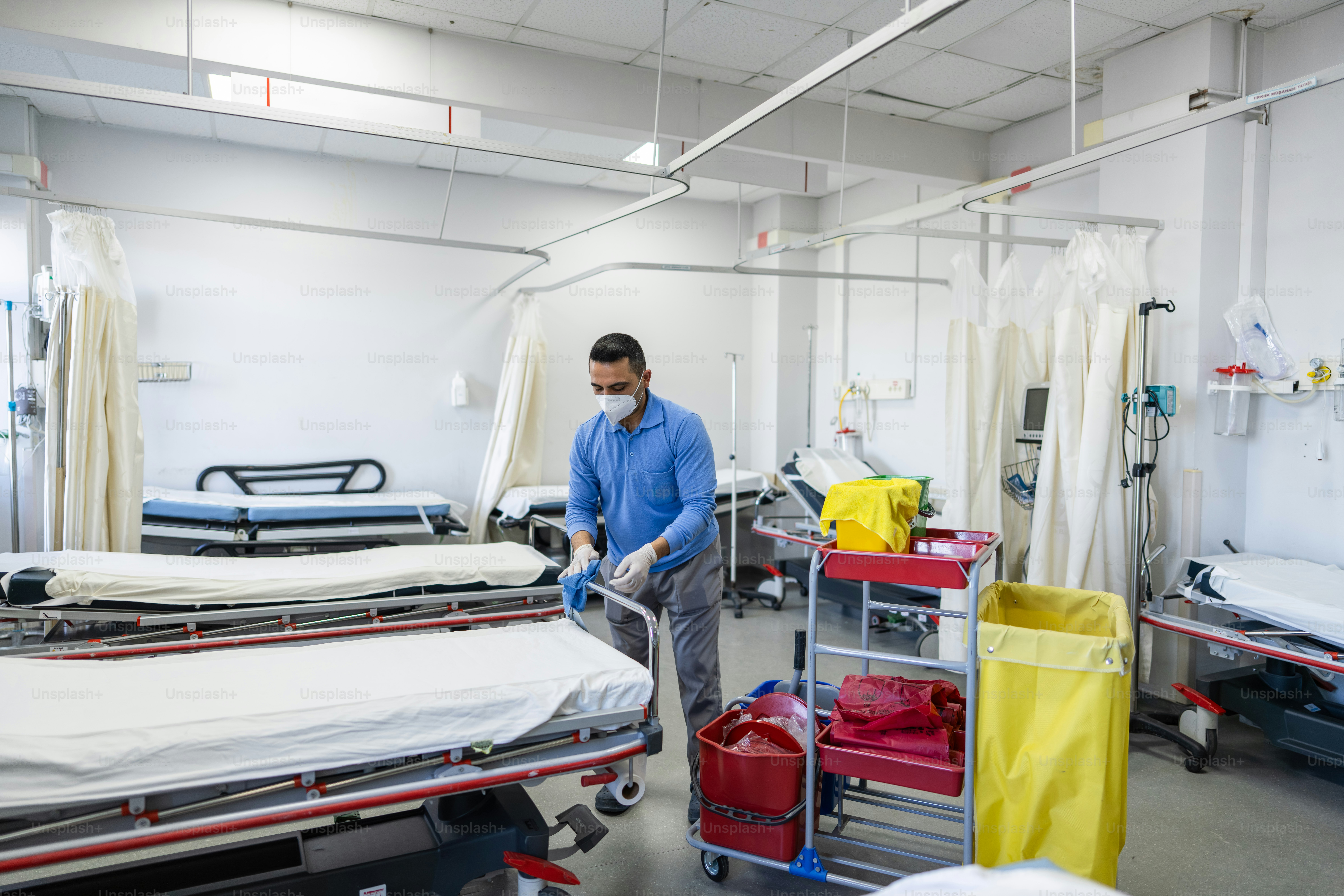Healthcare worker preparing hospital beds in empty ward