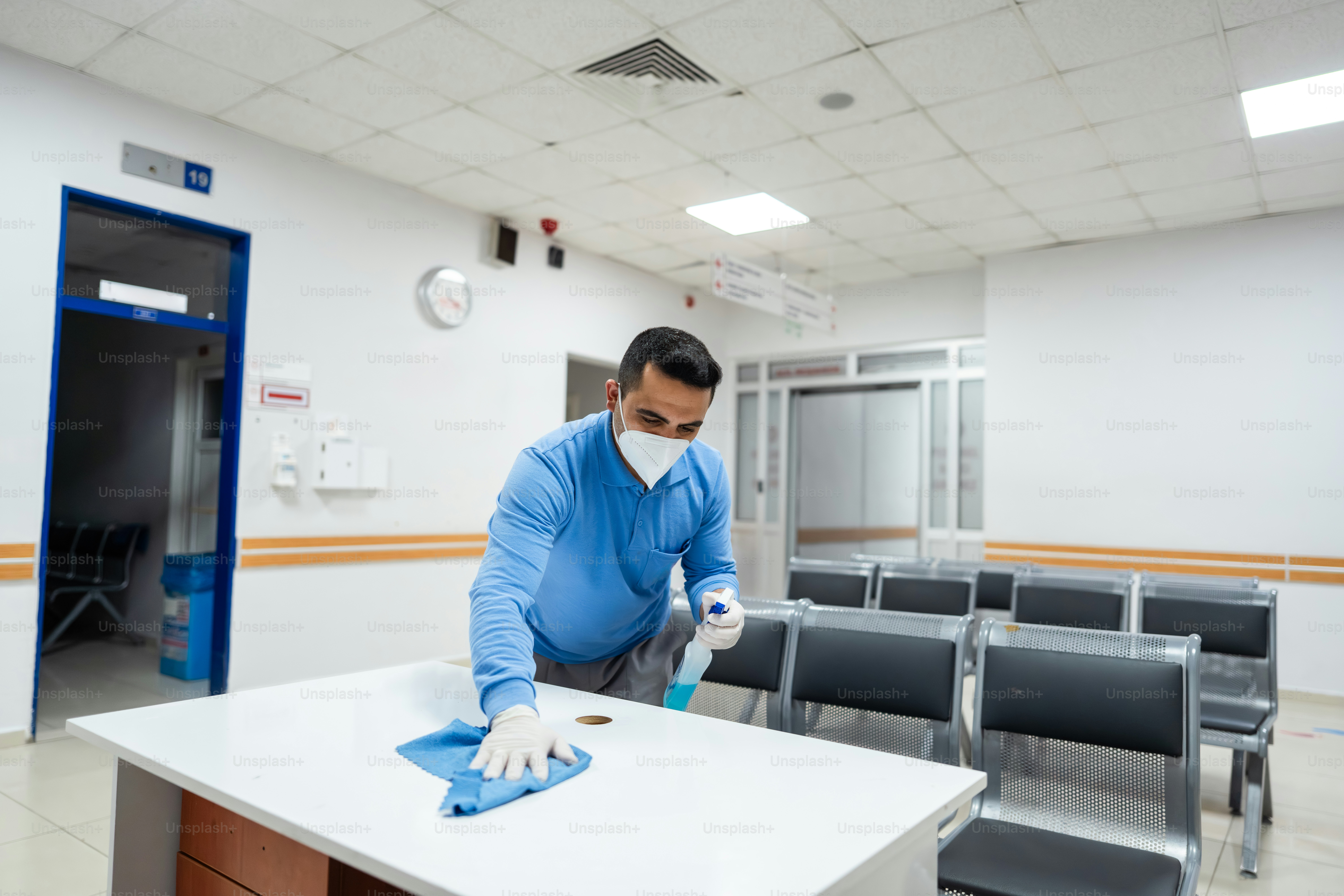 Man in mask cleans table in waiting room.