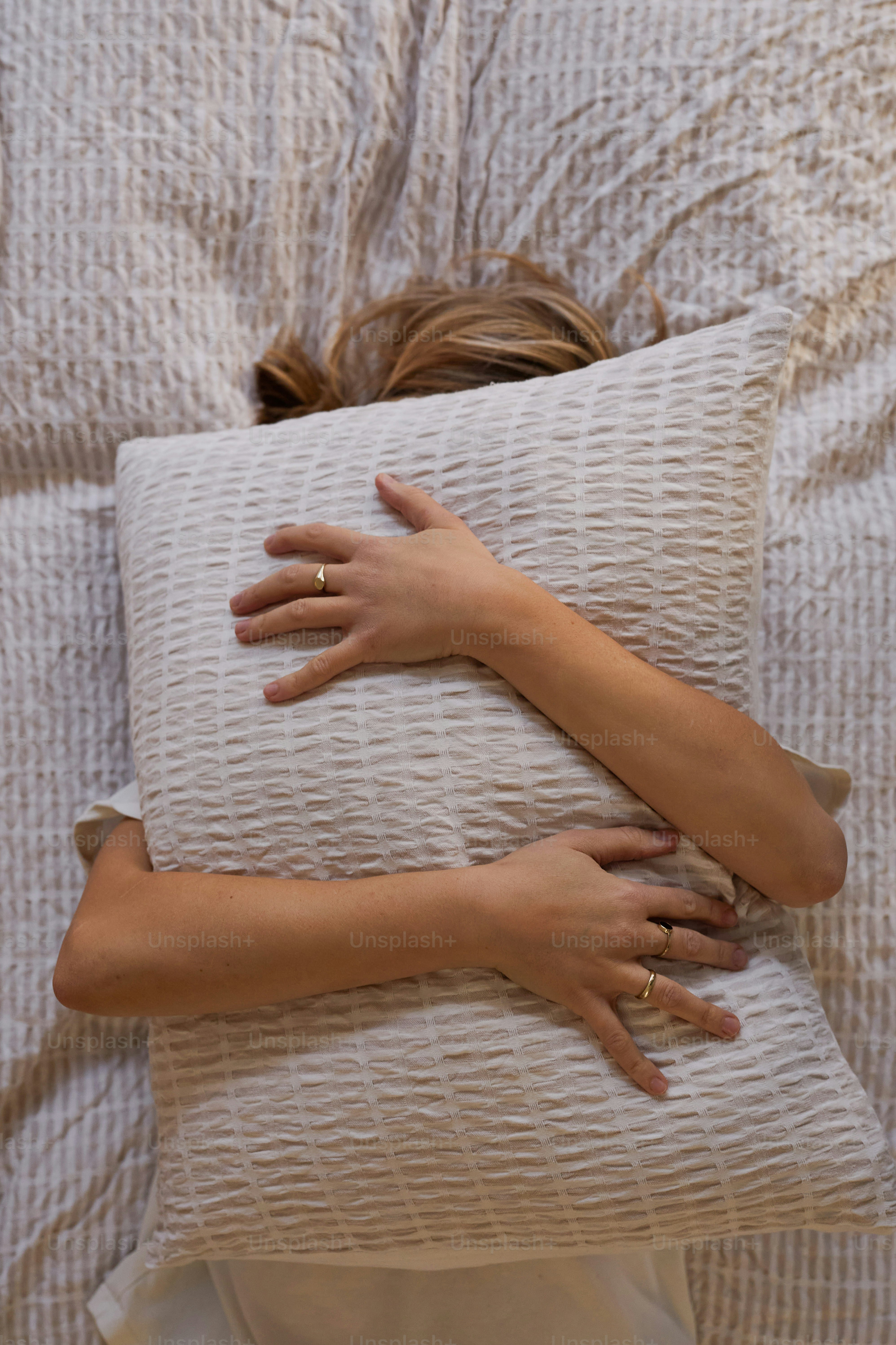 Woman hugging a pillow in bed