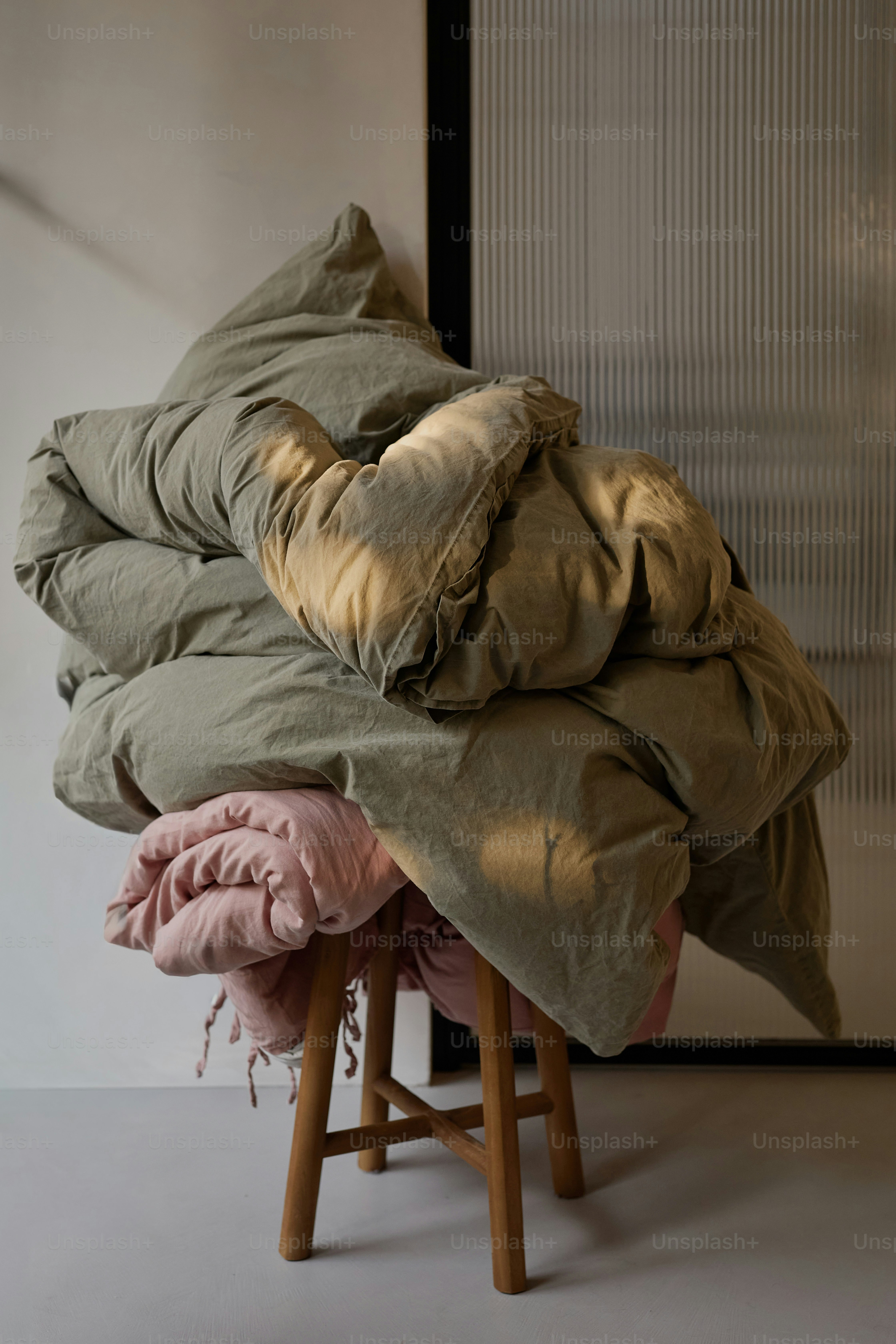 Pile of folded blankets on a wooden stool